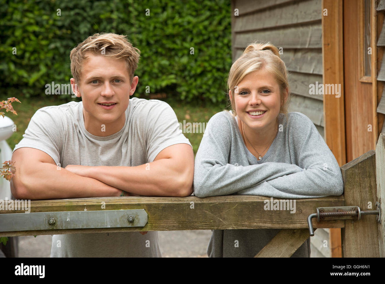 Portrait of a teenage couple leaning on a garden gate Stock Photo