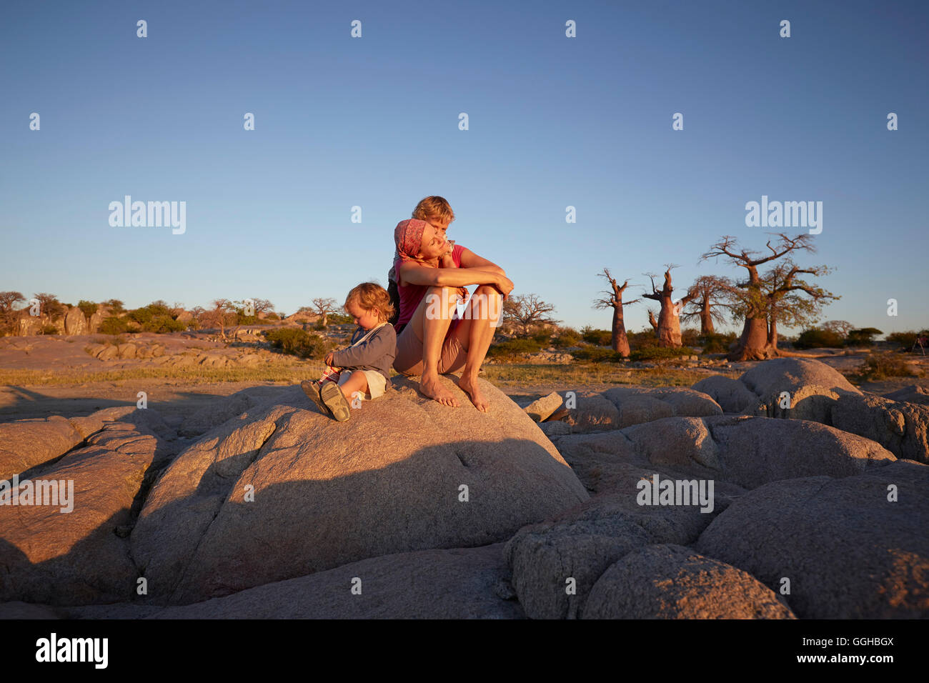 Mother and sons sitting on a rock, Kubu Island, Makgadikgadi Pans National Park, Botswana Stock Photo