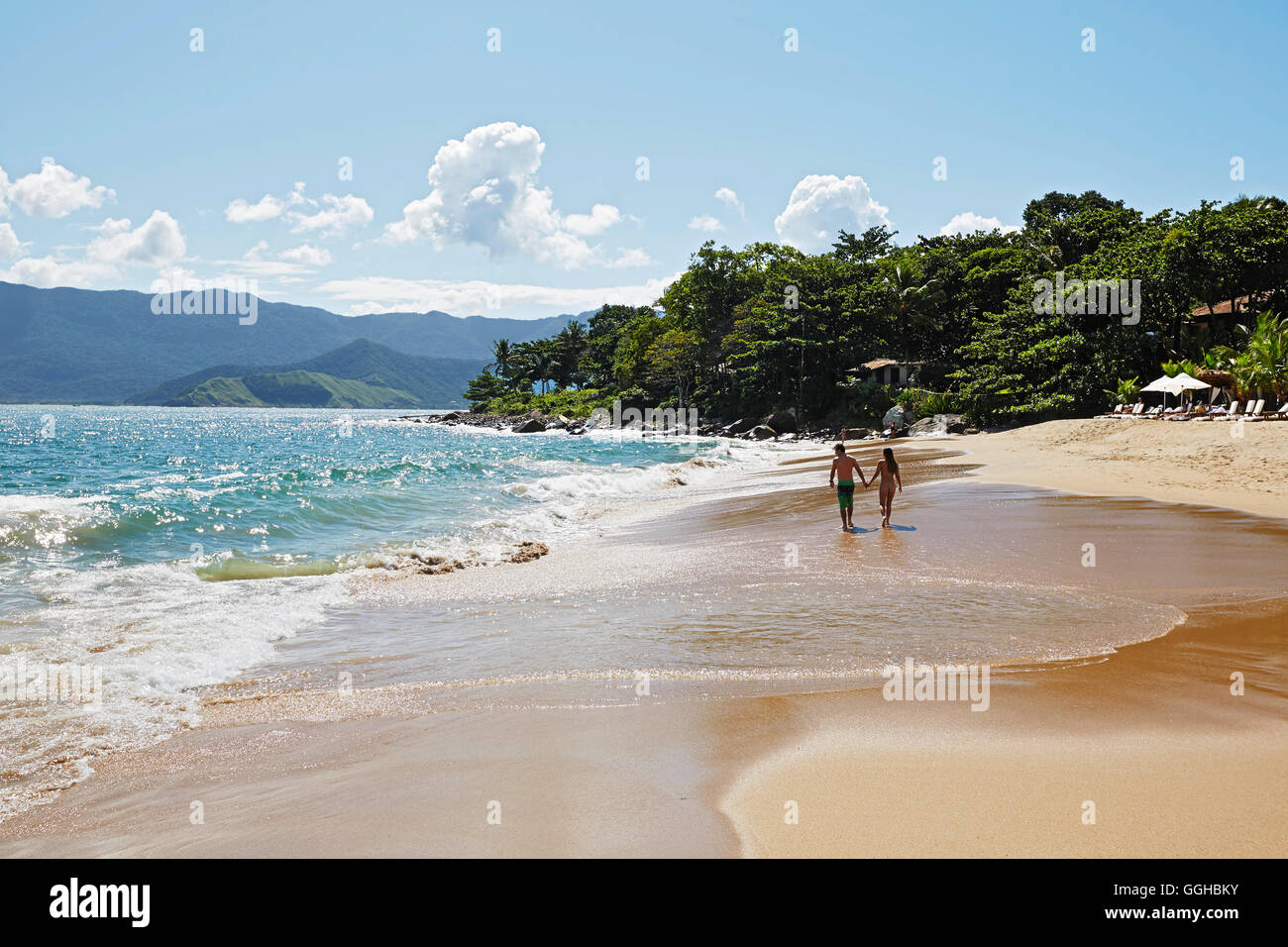 Couple walking hand in hand on the beach, Praia do Curral, western side of the island Ilhabela