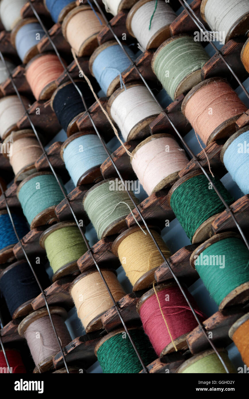 reels of colored cotton stored in European style rack that hangs on the wall Stock Photo