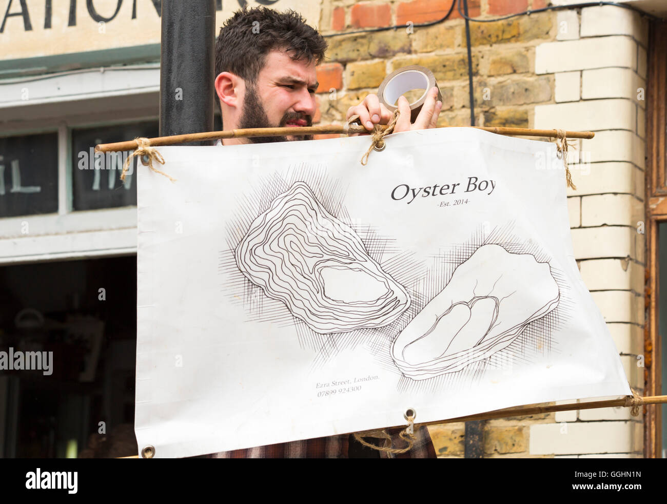 Oyster Boy putting up sign at Columbia Road market, London UK in July Stock Photo