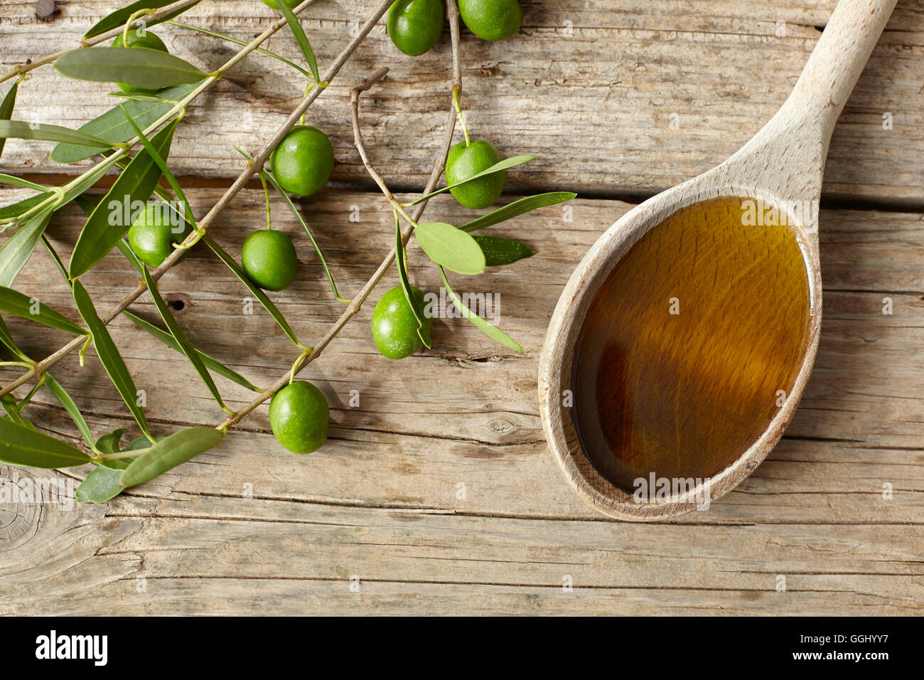 Green olive branch and a spoon full of oil on the wooden table Stock ...