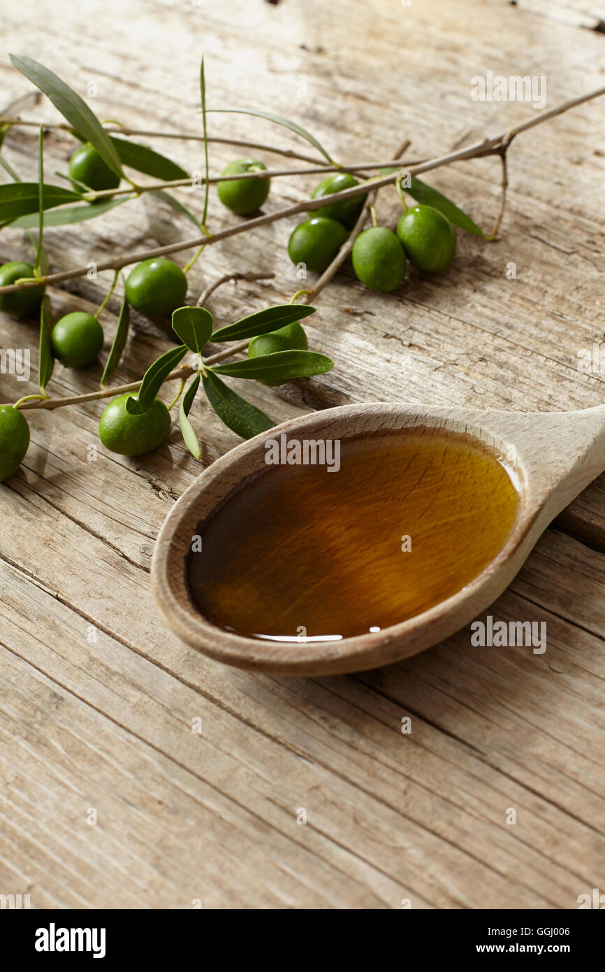 Green olive branch and a spoon full of oil on the wooden table Stock ...