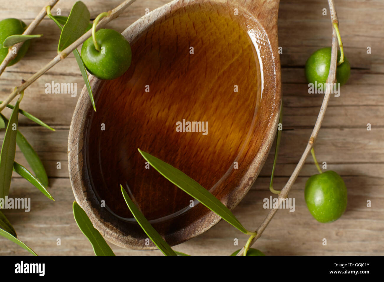 Green olive branch and a spoon full of oil on the wooden table Stock ...