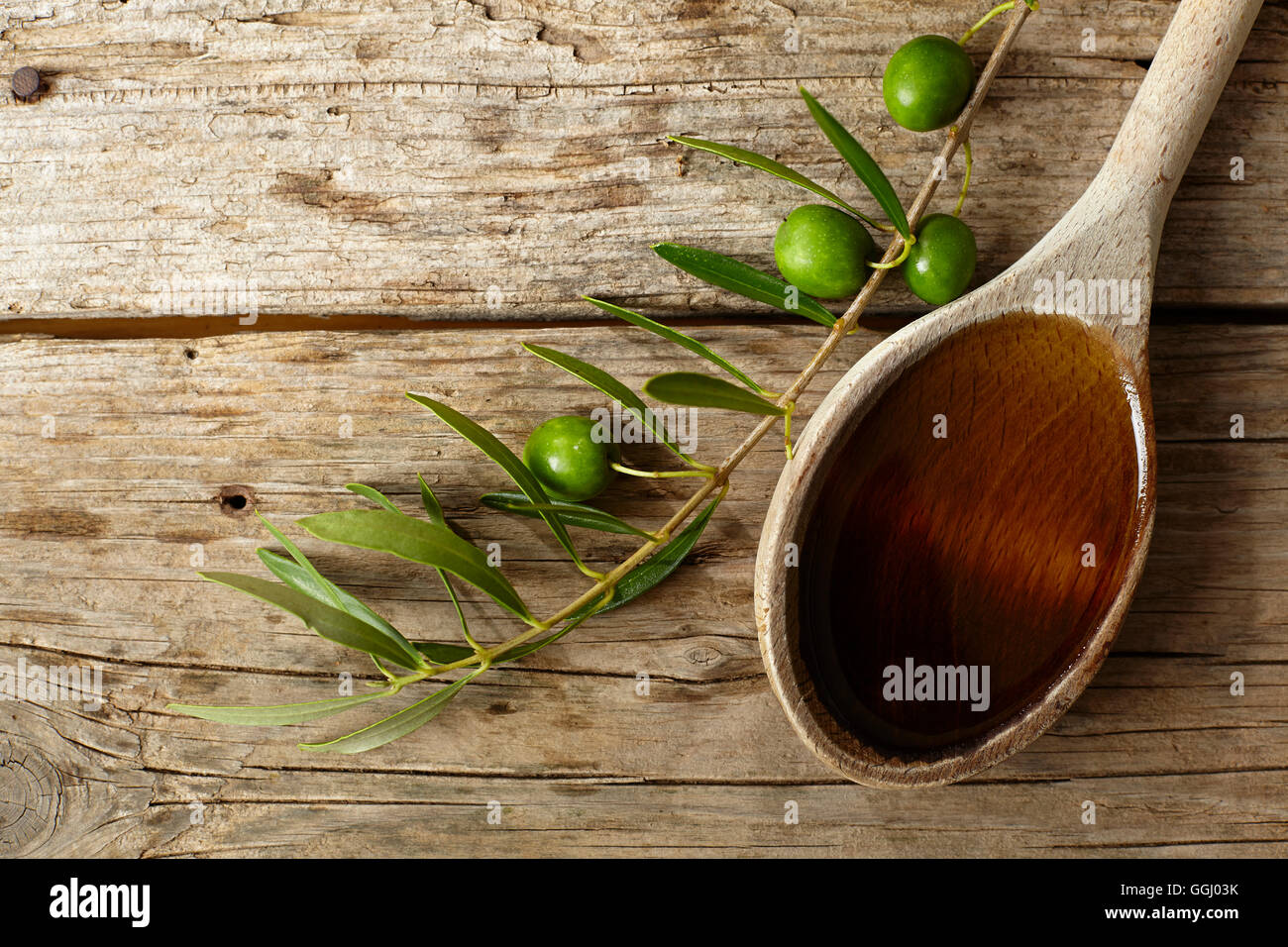 Green olive branch and a spoon full of oil on the wooden table Stock ...