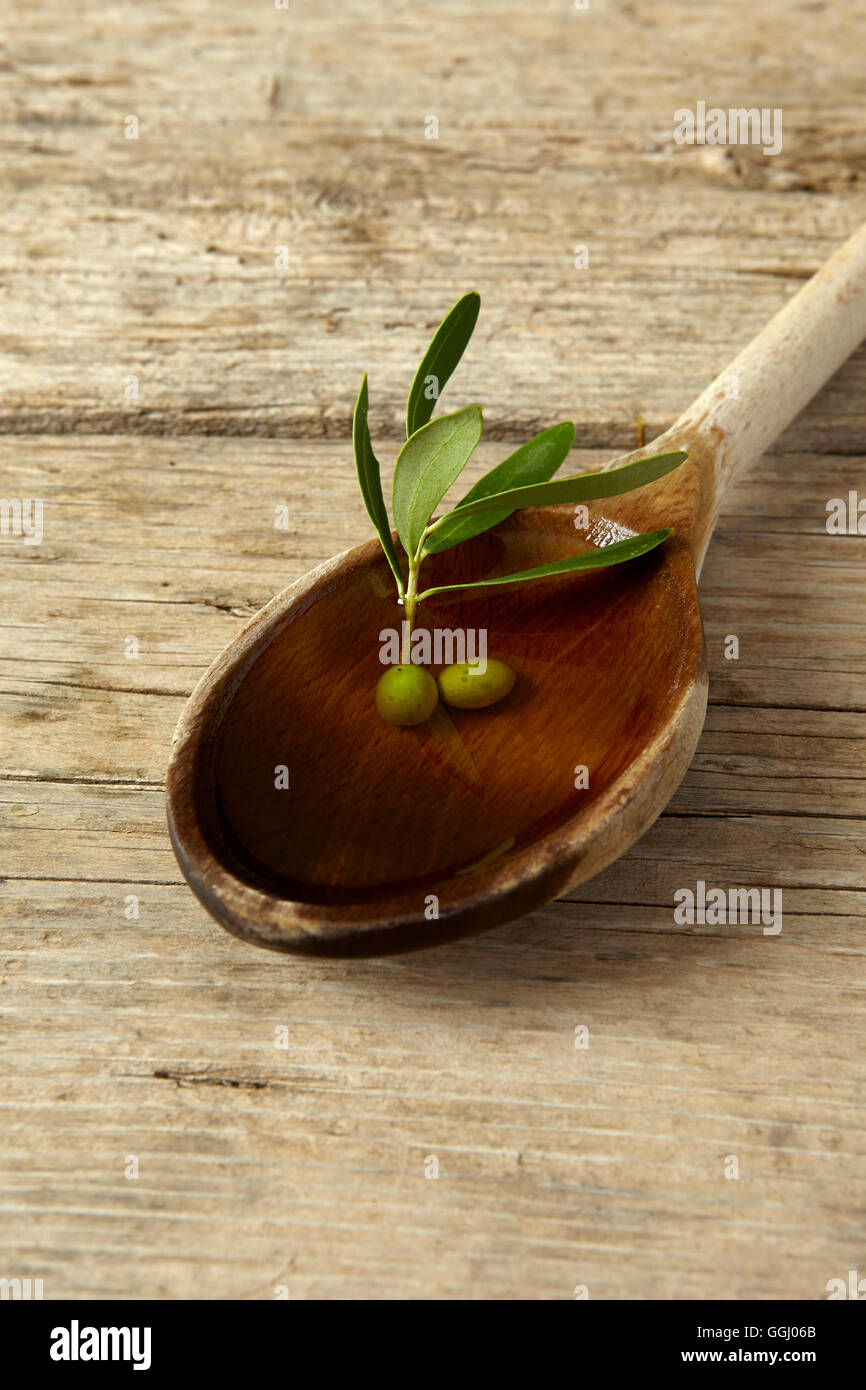 Green olive branch and a spoon full of oil on the wooden table Stock ...