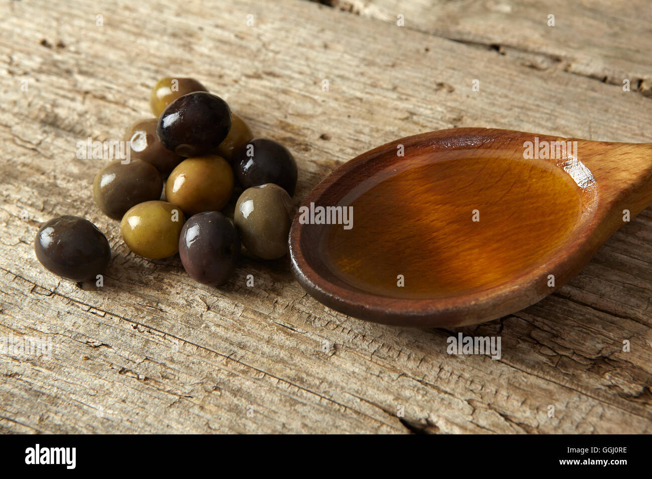 spoon full of olive oil and olives on a wooden table Stock Photo - Alamy