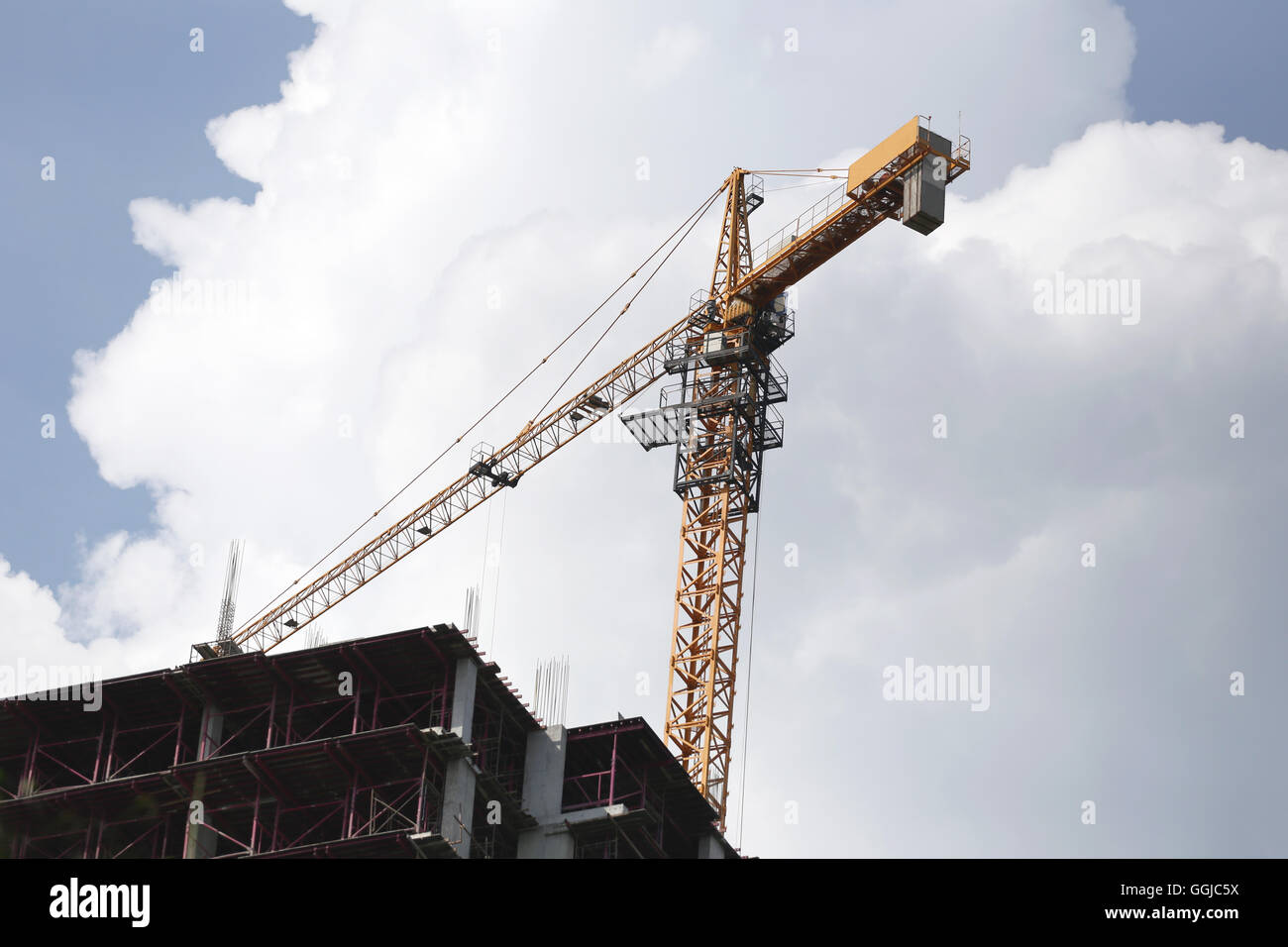 Crane working on a building under construction in day time. Stock Photo