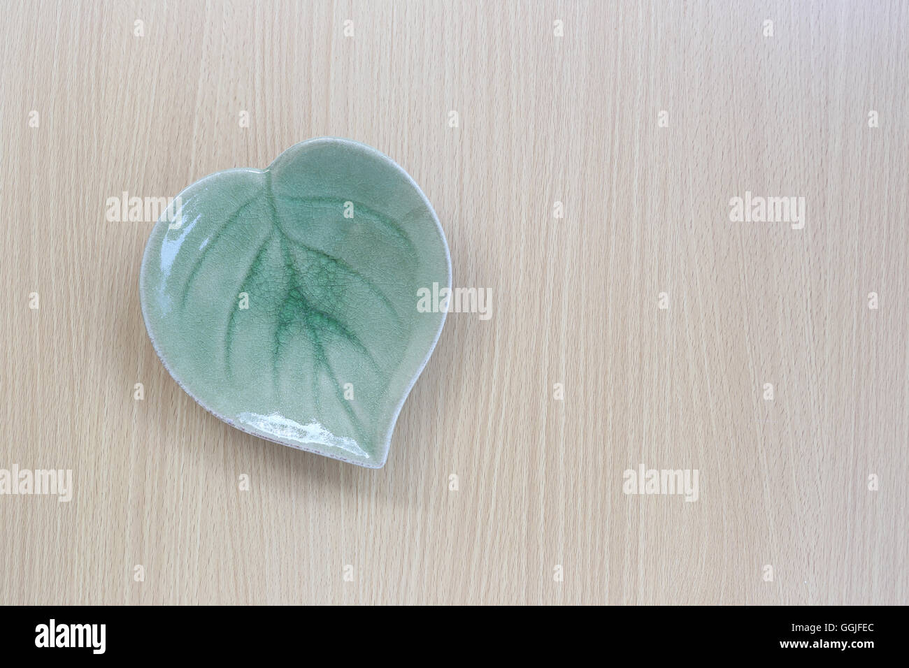Green leaf shape dish in top view on wood background for design concept food. Stock Photo