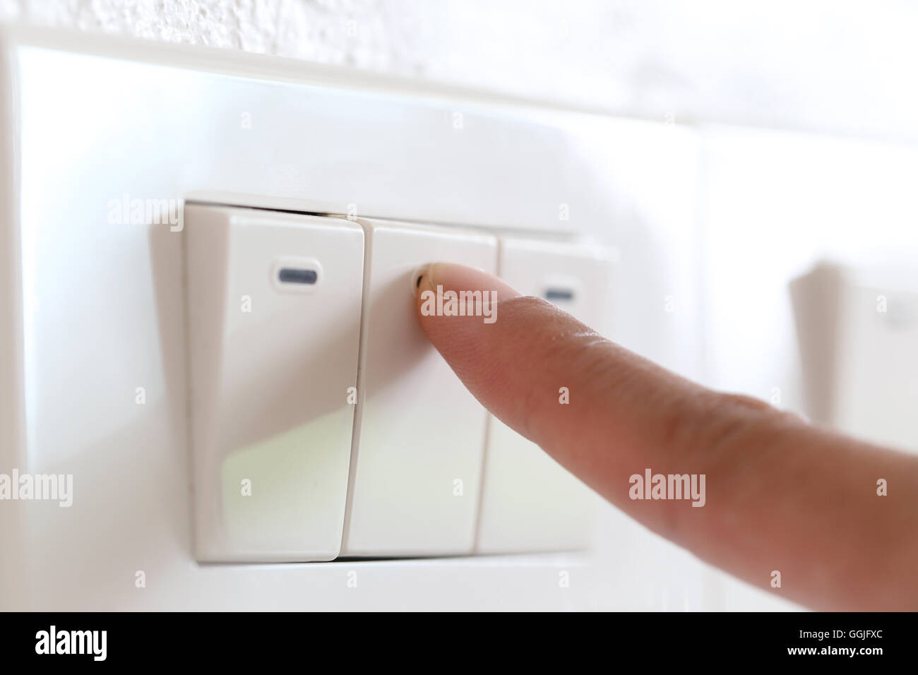 fingers are off light switch in the house,concept for energy saving reduce global warming. Stock Photo