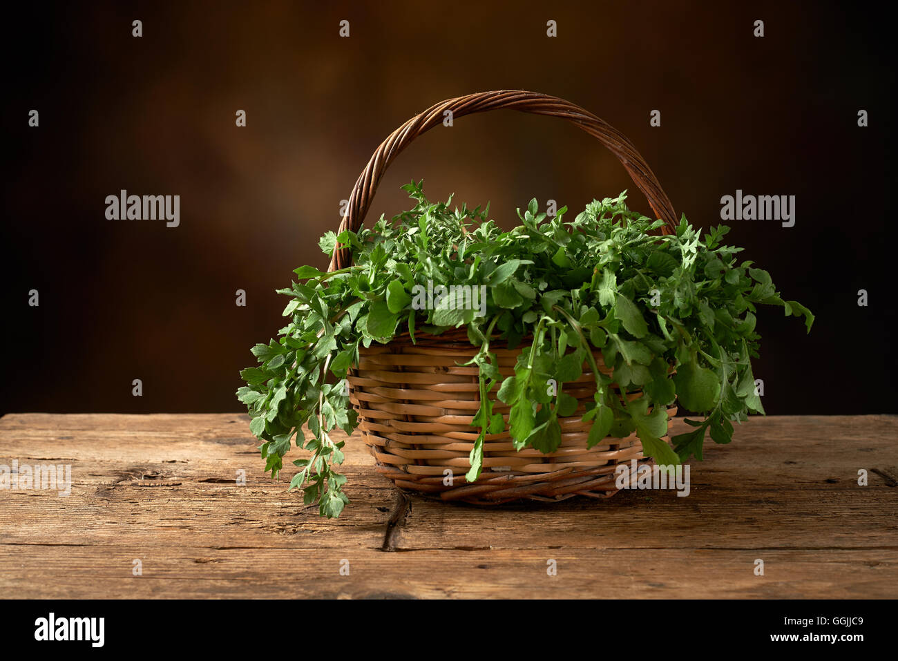 fresh green leafy vegetable on a wooden kitchen bench. Stock Photo
