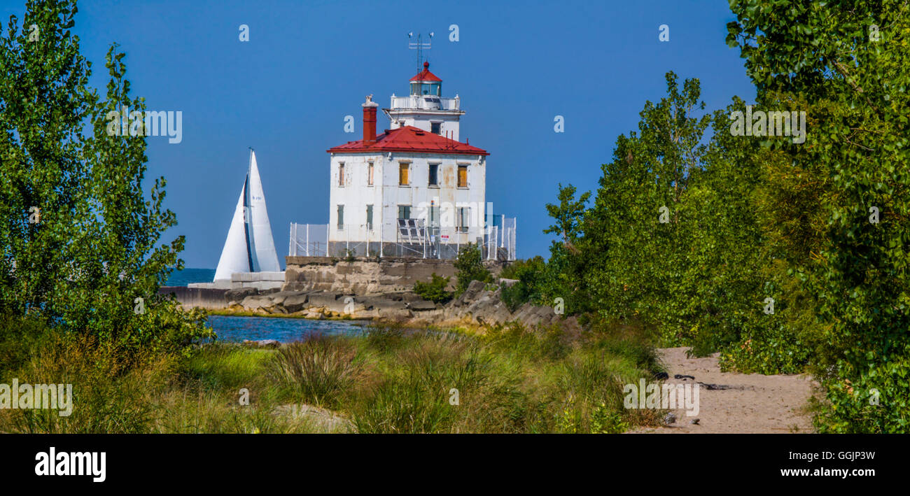 A classic Lake Erie lighthouse, The Fairport Harbor West Breakwater Light in Fairport Ohio as a sailboat passes by, USA Stock Photo