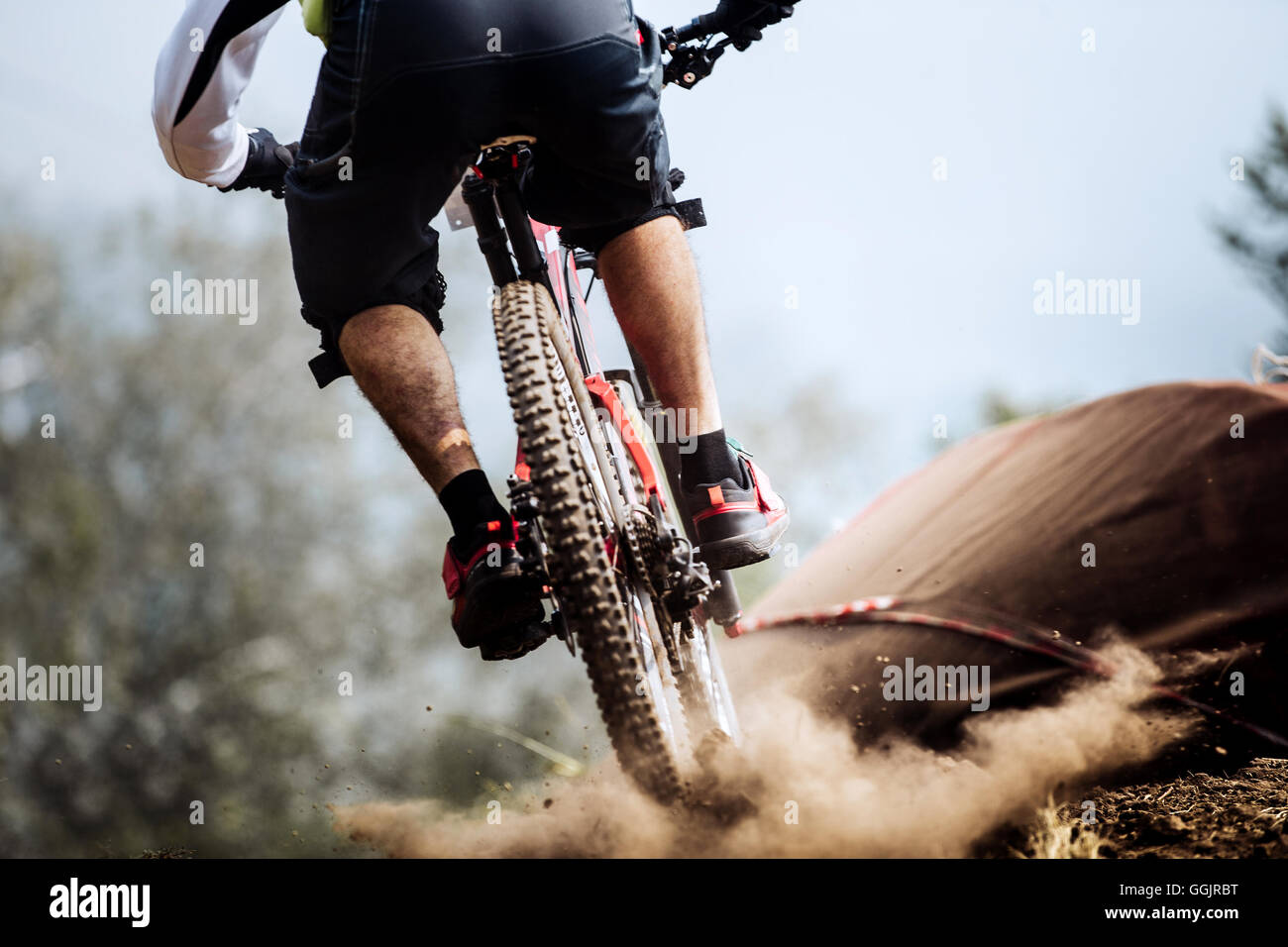 closeup of rear wheel of bike extreme racer on track downhill, dust