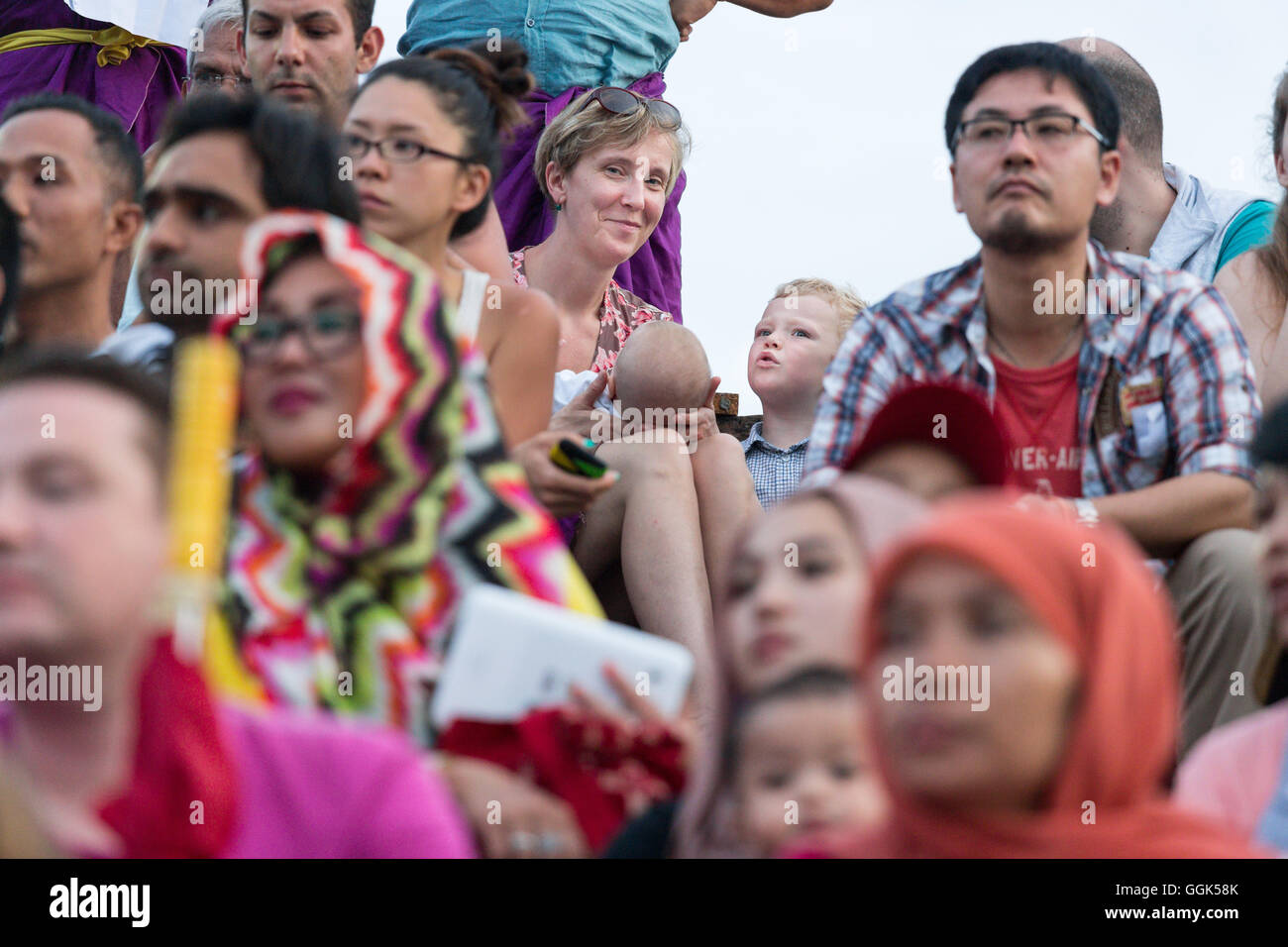 Mother, 3 year old boy, baby, among an international audience at a Balinese dance show, western family, family travel in Asia, p Stock Photo