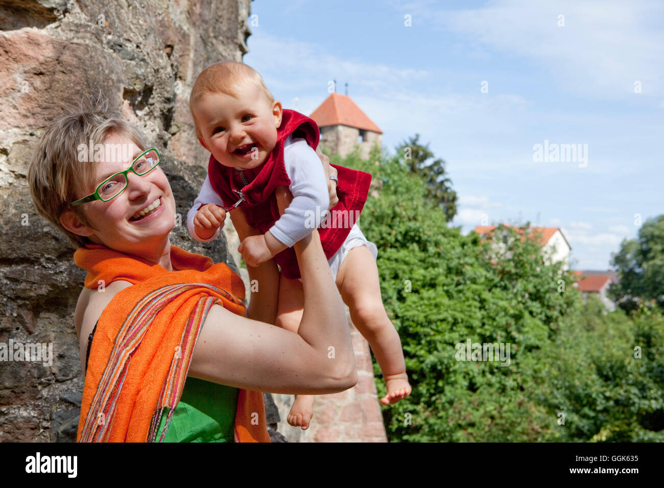 Young smiling woman lifting her laughing baby at the Fritzlar city wall, Fritzlar, Hesse, Germany, Europe Stock Photo
