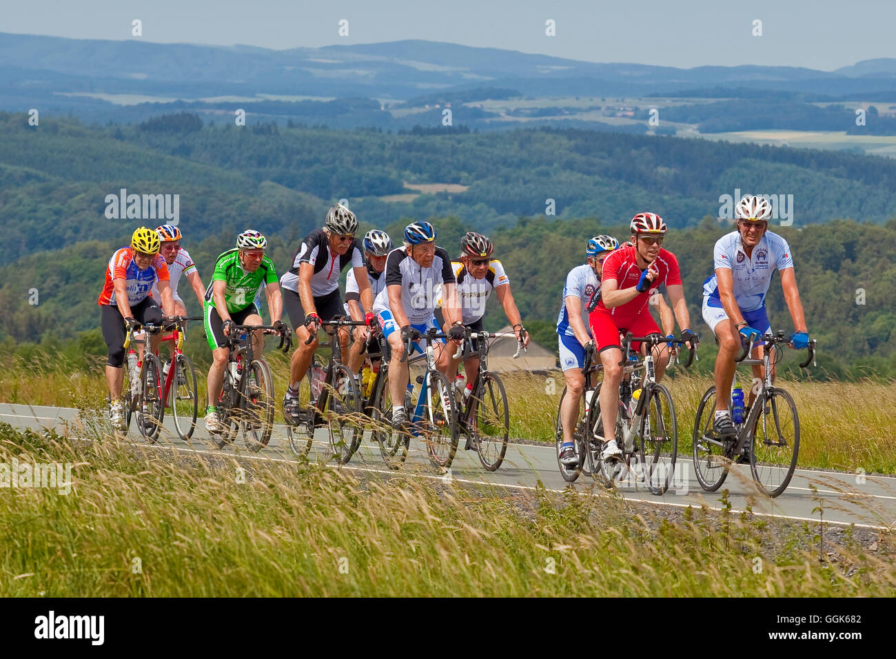 A group of cyclists cycling up a hill with Frankenberger Land behind