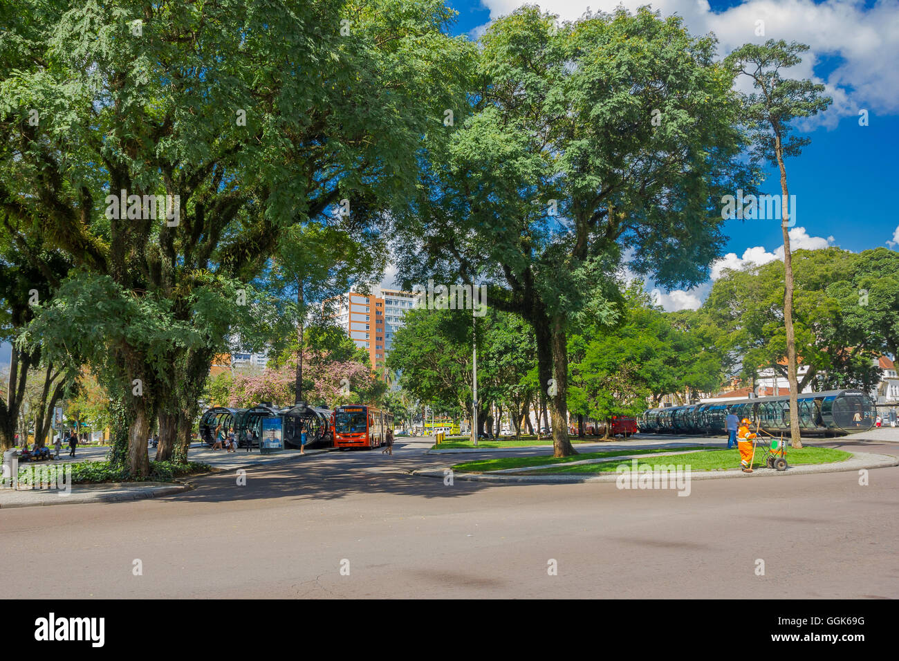 CURITIBA ,BRAZIL - MAY 12, 2016: bus stations located in the middle of a park, big trees in front of the bus stations and some buildings as background Stock Photo