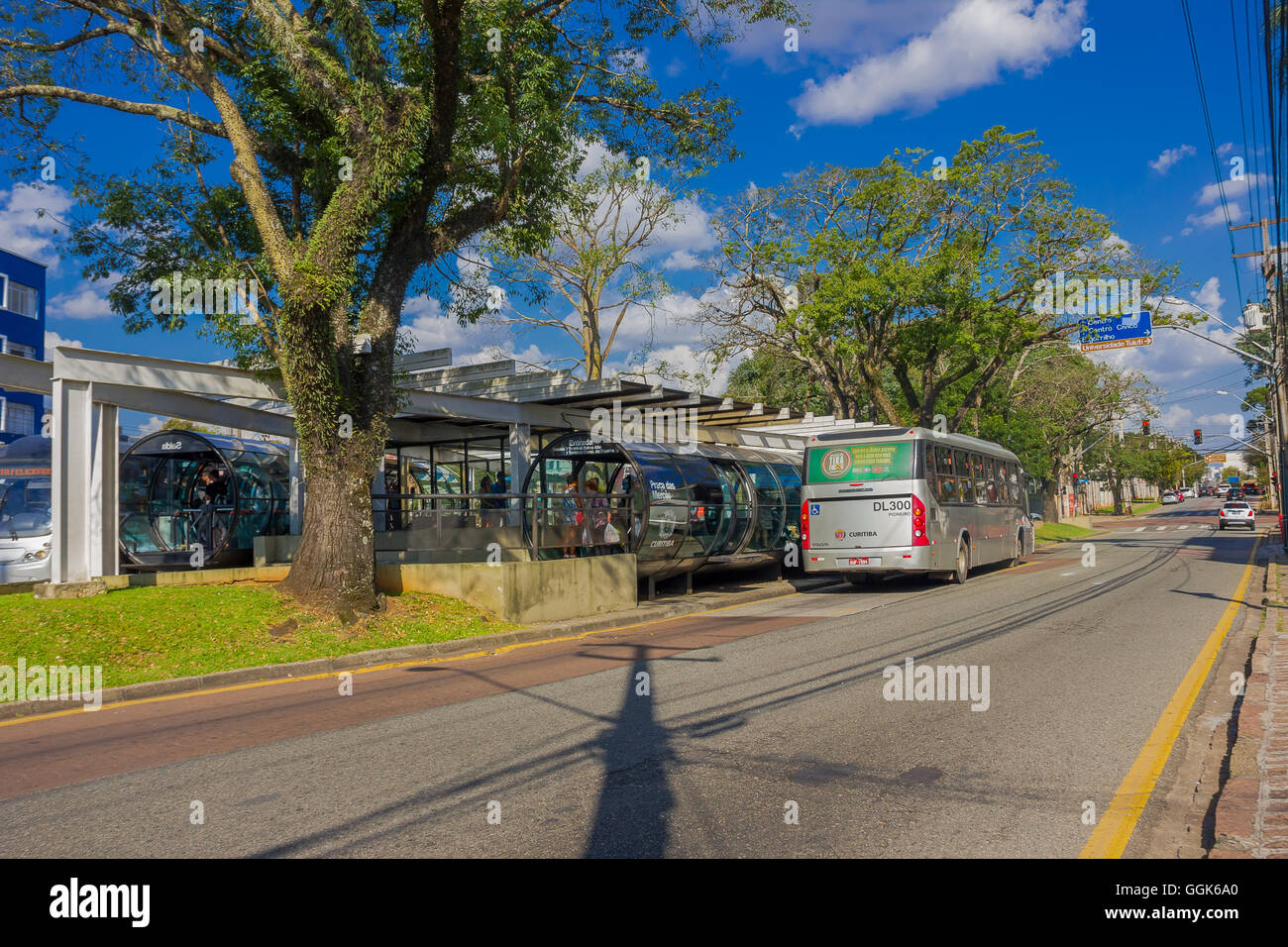 CURITIBA ,BRAZIL - MAY 12, 2016: passengers getting on a public bus, big tree located next to the bus station Stock Photo