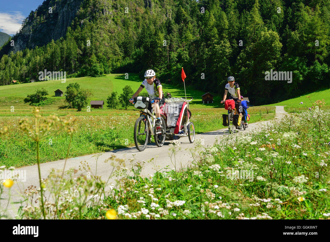 Two cyclists with child trailer riding along Inn cycle route, Zams, Tyrol, Austria Stock Photo