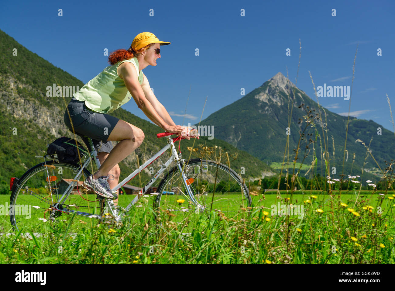 Woman cycling along Inn cycle route, Tschirgant in background, Mils, Tyrol, Austria Stock Photo