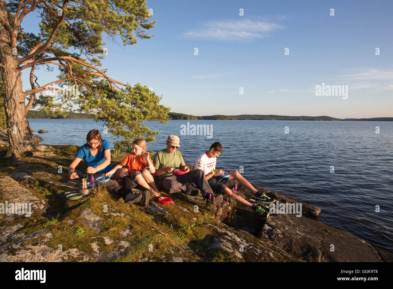 Family having dinner on a rock at lake Vaermeln, Vaermland, Sweden Stock Photo