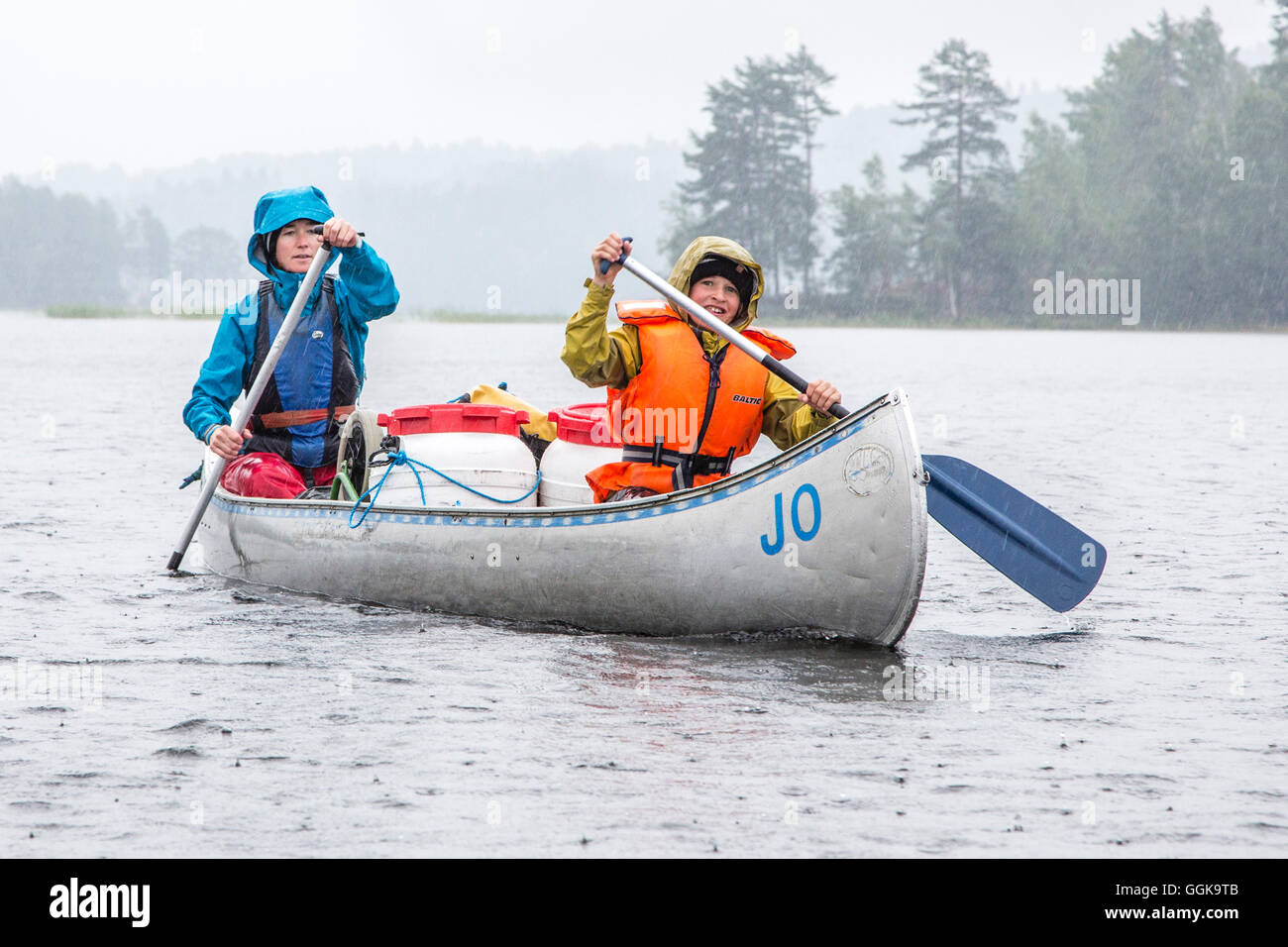 A woman and a boy in a canoe in the rain on lake Vaermeln, Vaermland, Sweden Stock Photo