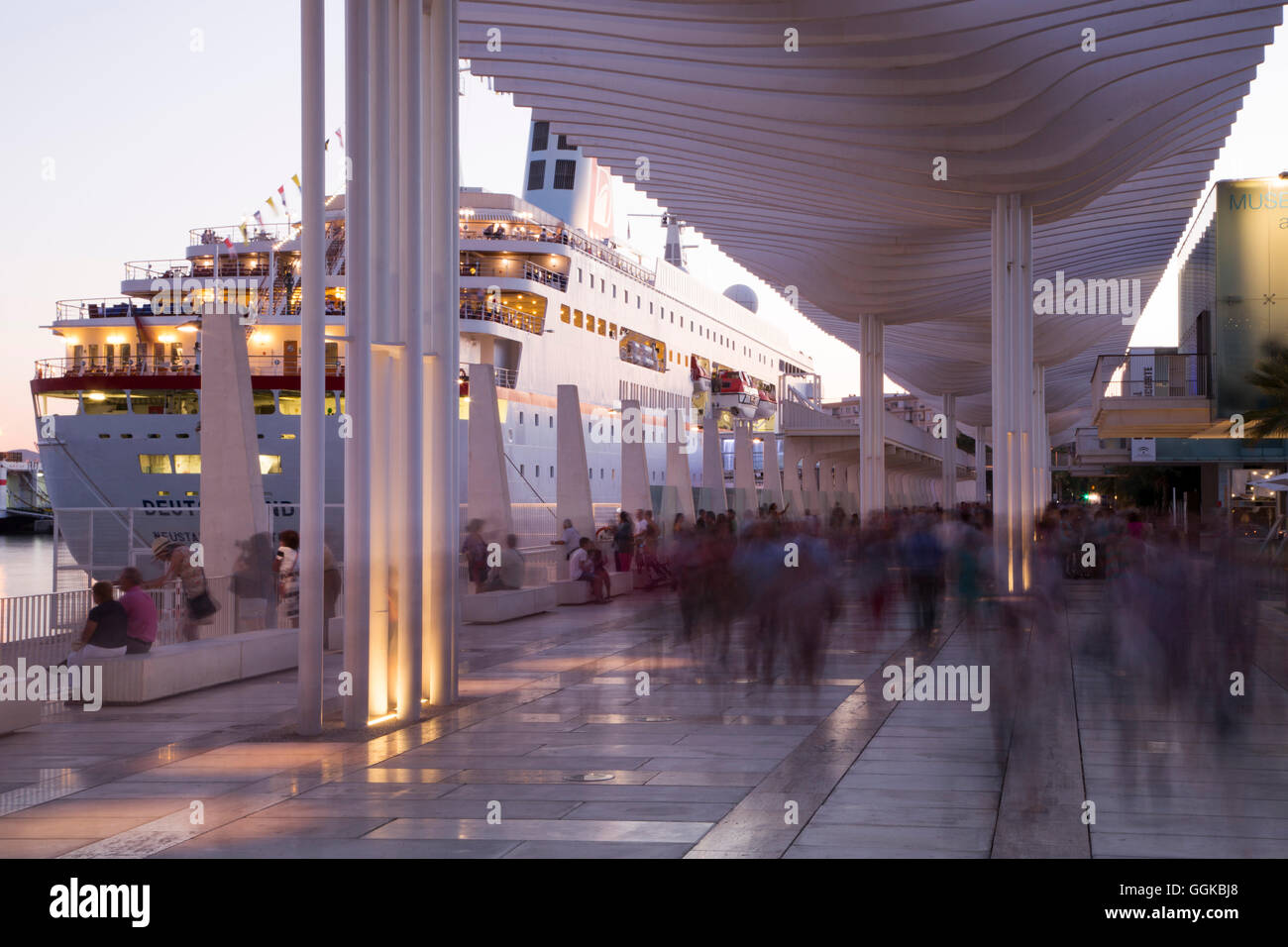 Long exposure of people walking past Malaga Cruise Terminal and cruise ship MS Deutschland (Reederei Peter Deilmann) at dusk, Ma Stock Photo