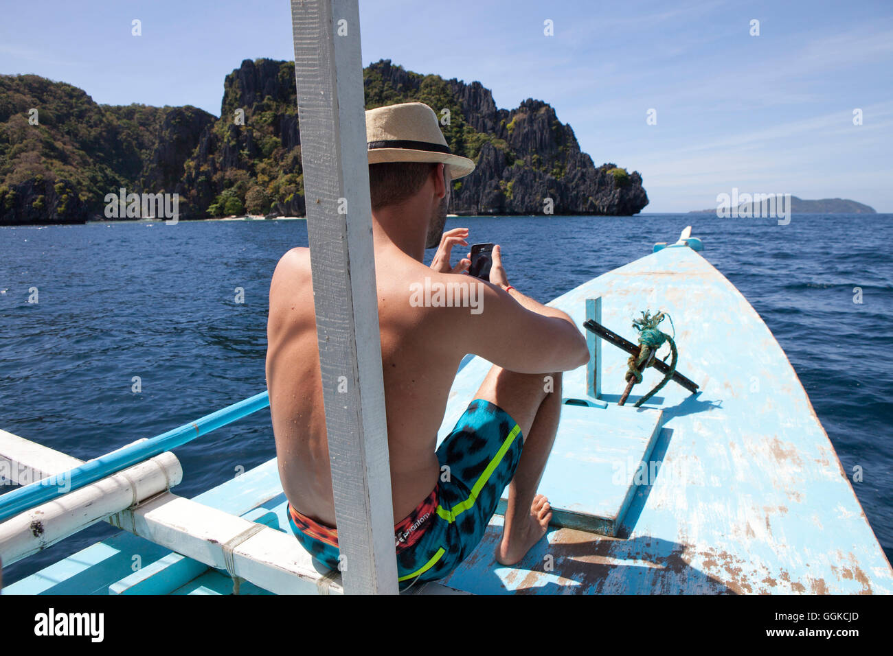 Young man with mobile phone on a boat in the Archipelago Bacuit near El Nido, Palawan Island, South China Sea, Philippines, Asia Stock Photo