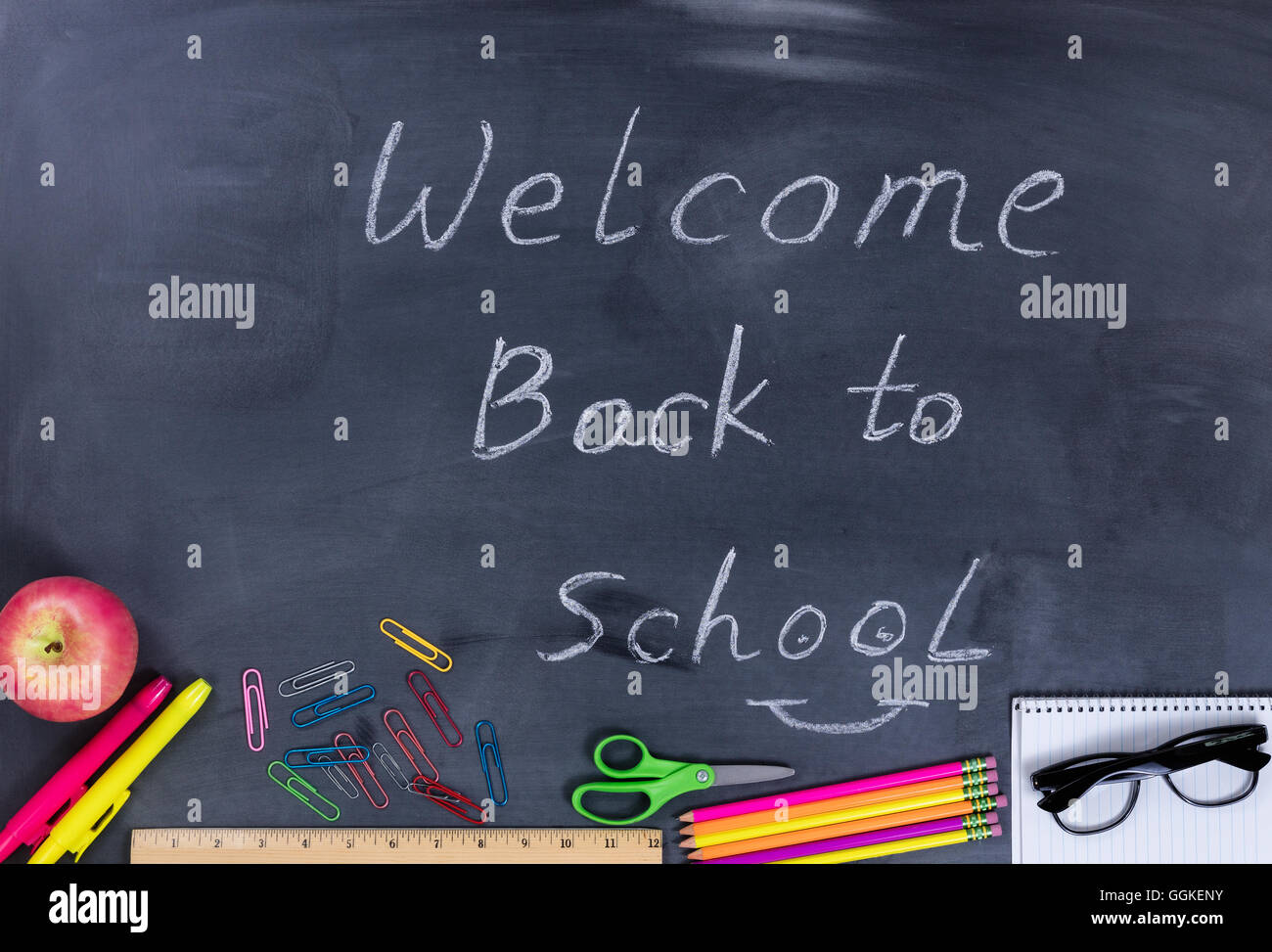 Back to school concept with supplies on chalkboard with written message ...