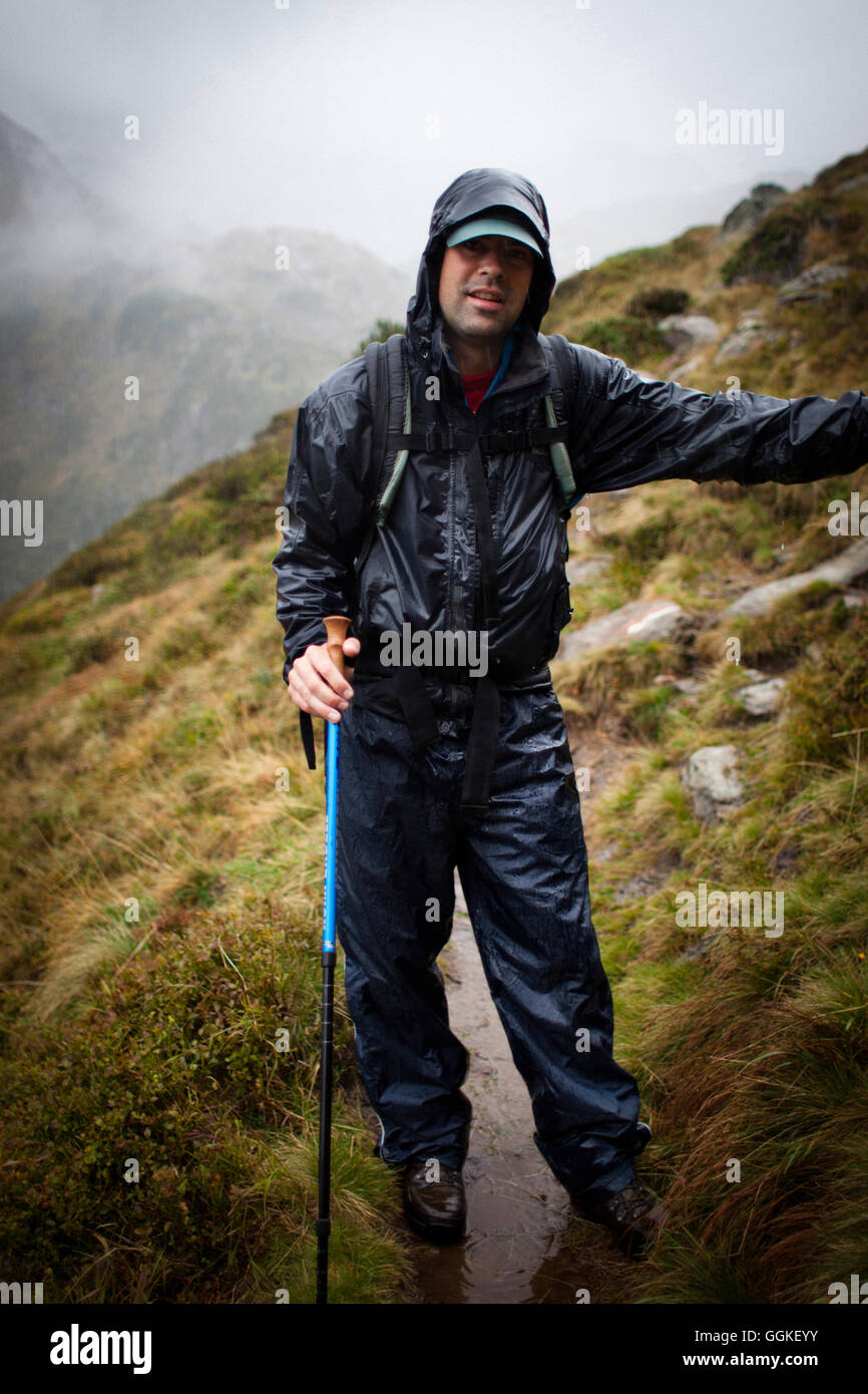 Man in rainy weather on a mountain trail, descent from Bremer Hut (2413 m), rear of Gschnitz Valley, Stubai Alps, Tyrol, Austria Stock Photo