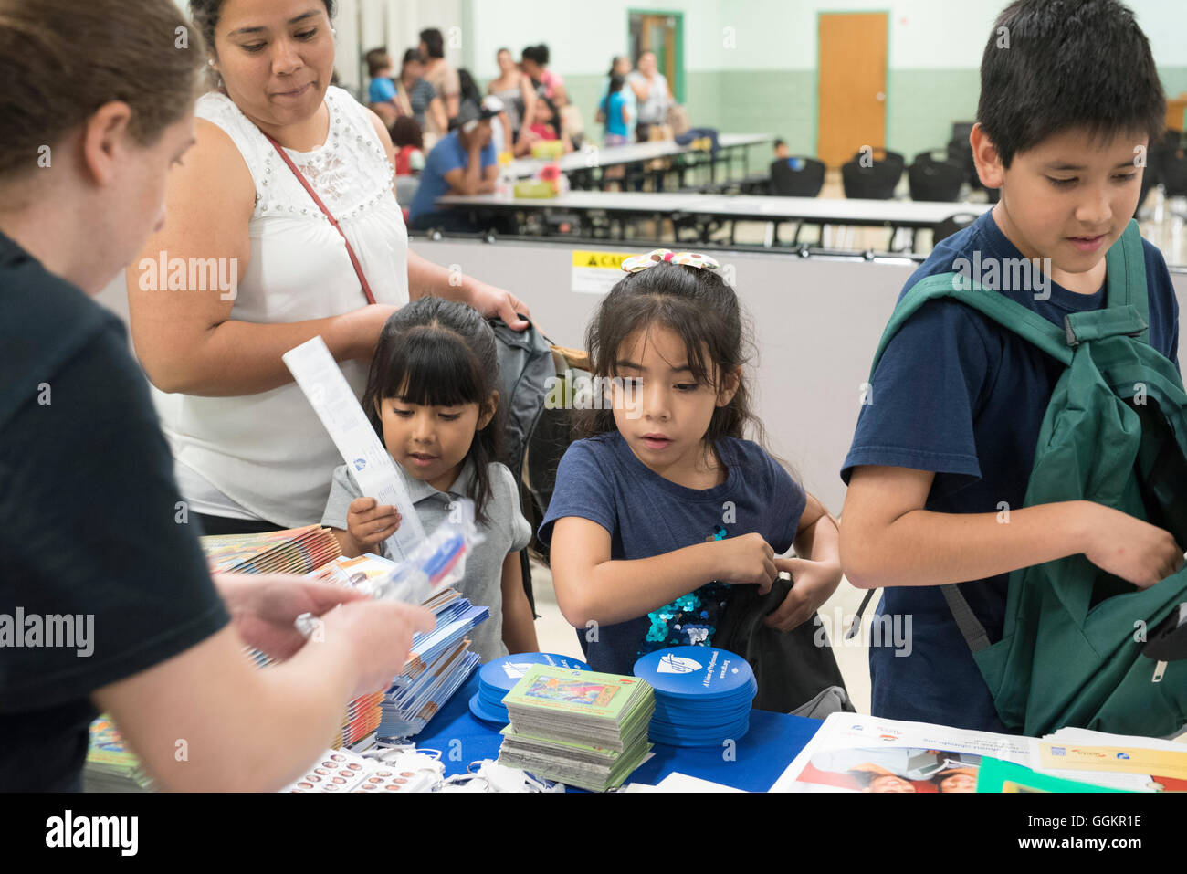Kids and parents look through free school supplies and books at summer