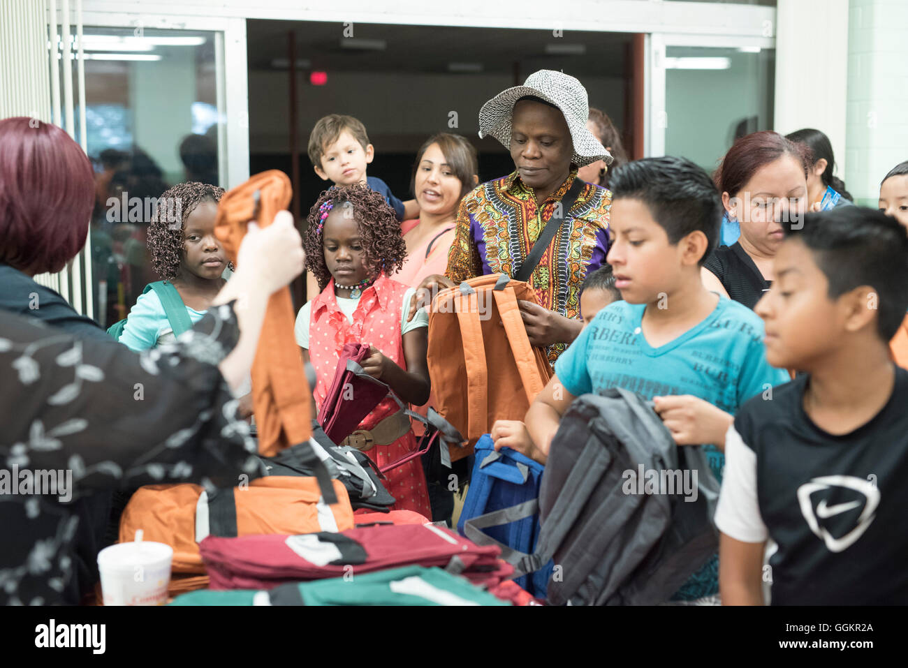 Kids and parents look through free school supplies at summer program for English language learners in Austin TX Stock Photo