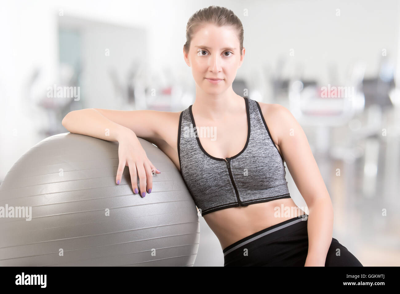 Fit woman standing and holding a pilates ball, in a gym Stock Photo