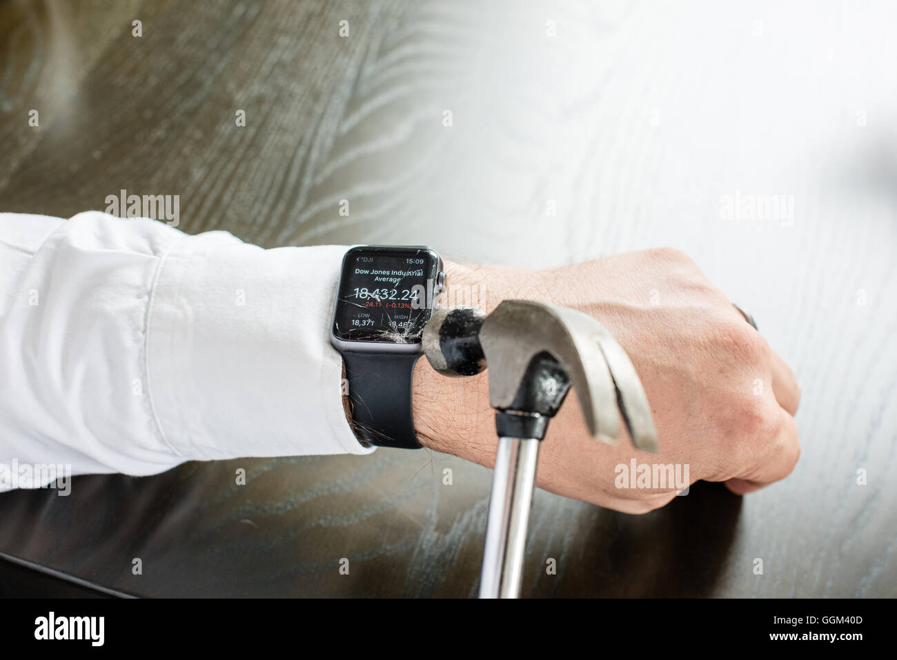 Ostfildern, Germany - July 31, 2016: A businessman wearing a white shirt is destroying the Apple Watch on his wrist using a hamm Stock Photo