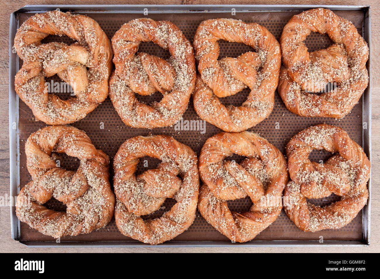 Soft pretzels spread with nuts and sugar holding on brown waxed paper