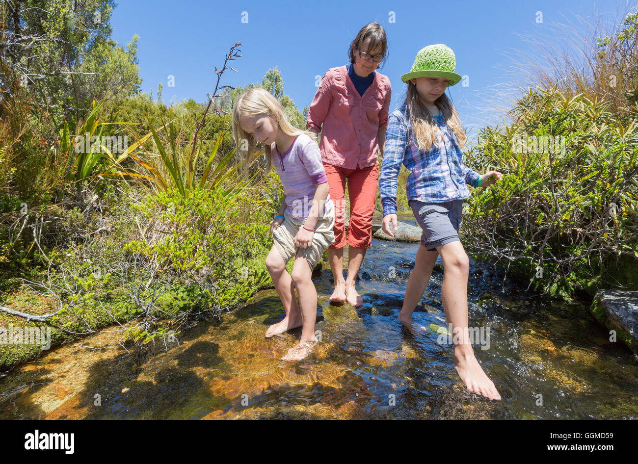 Two girls and an woman wading barefoot in a creek, Abel Tasman National Park, South Island, New Zealand Stock Photo