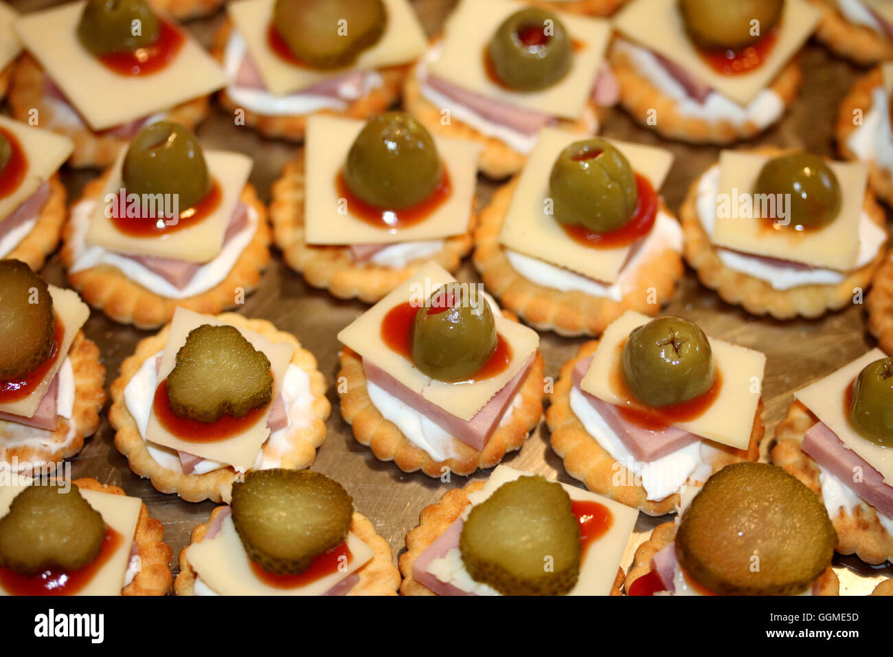 Closeup of crackers with cheese, ham, olives and ketchup Stock Photo
