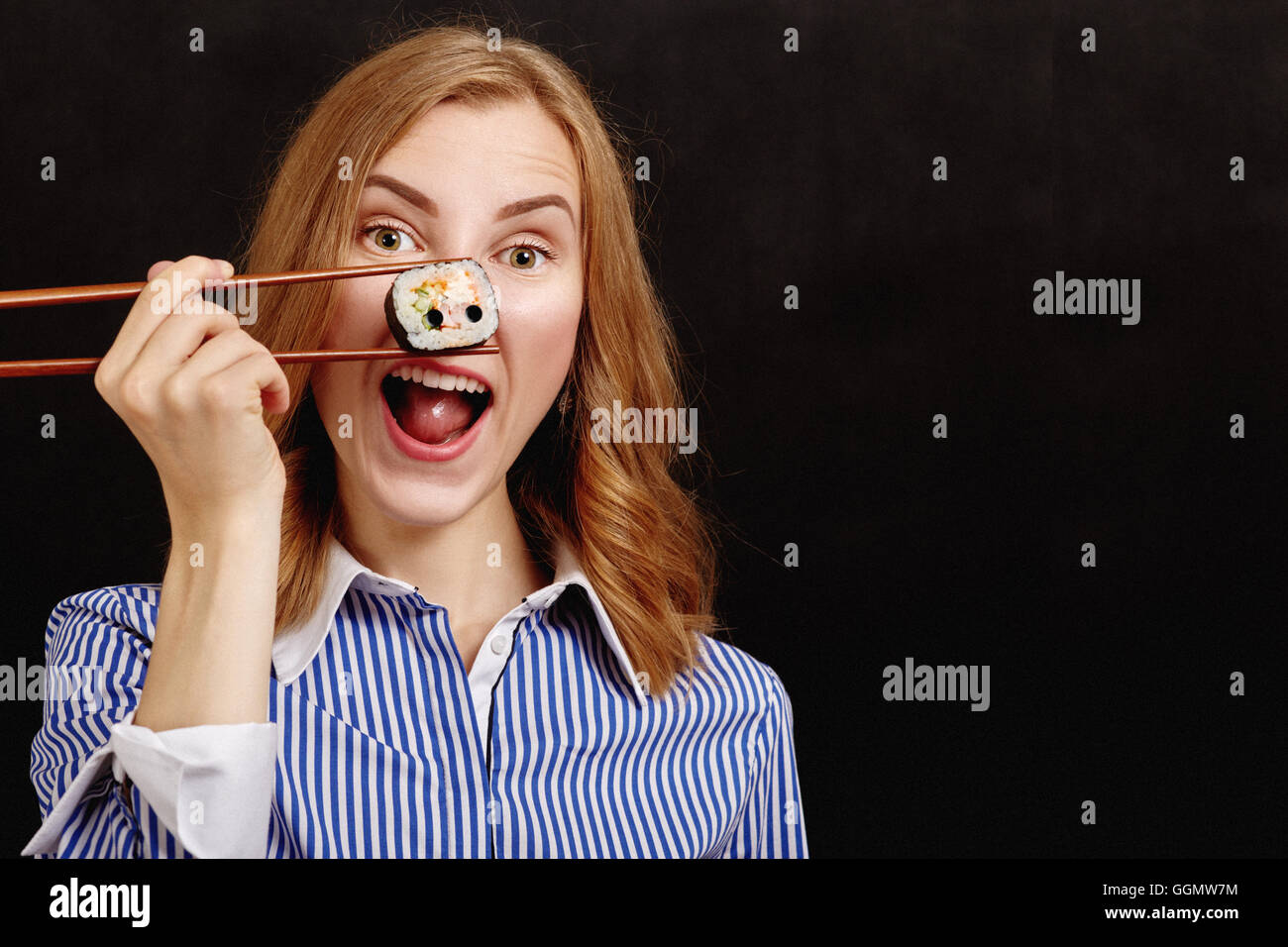 fun girl show snout with sushi roll on black background with copyspace Stock Photo
