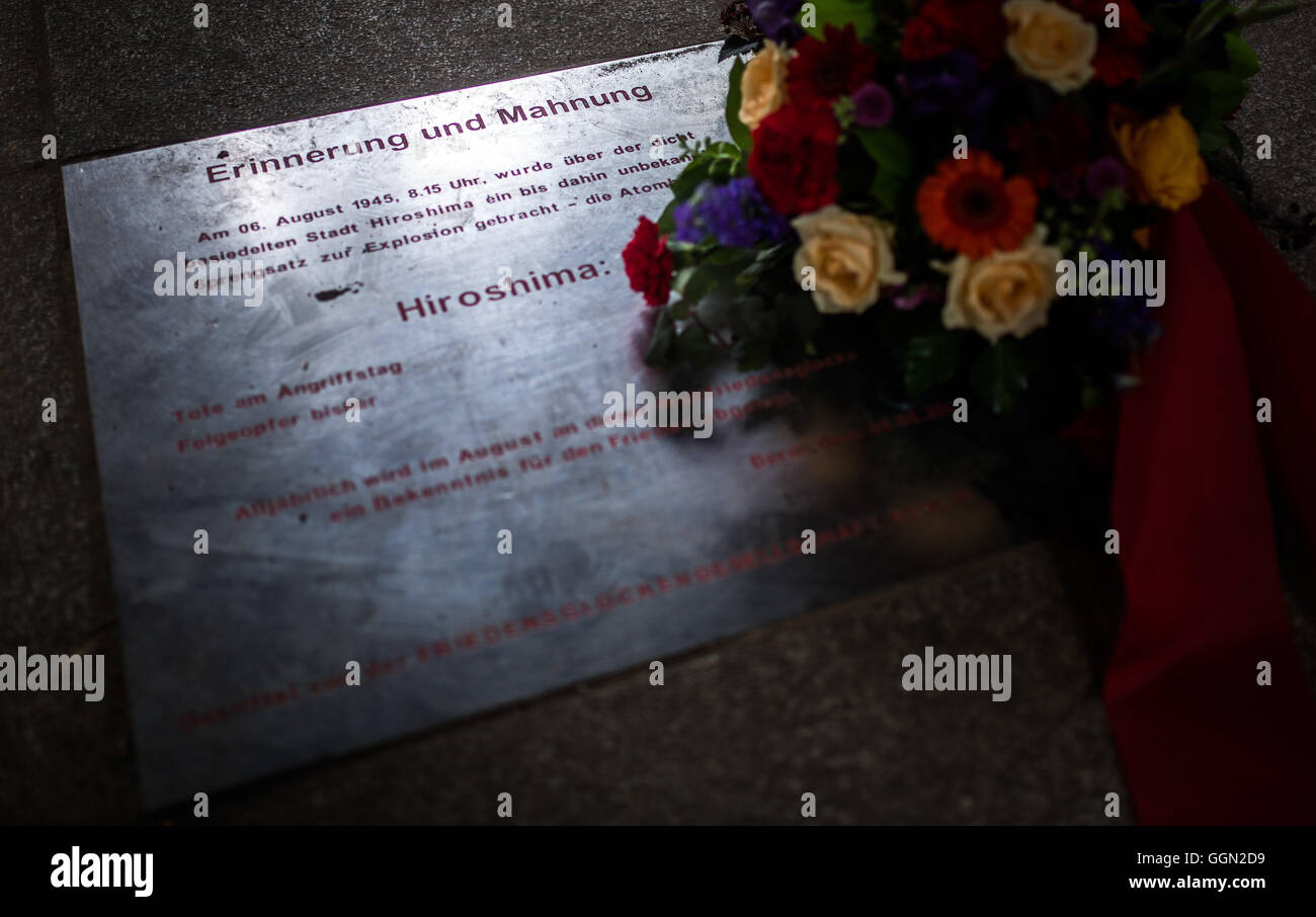 Berlin, Germany. 06th Aug, 2016. A bouquet of flowers lies on the memorial plaque for the victims of the atomic bombings in Hiroshima and Nagasaki in Volkspark Friedrichshain park in Berlin, Germany, 06 August 2016. The Peace Bells rang Saturday morning to commemorate the victims of the atomic bombings in Hiroshima (06 August 1945) and Nagasaki (09 August 1945). Photo: SOPHIA KEMBOWSKI/dpa/Alamy Live News Stock Photo