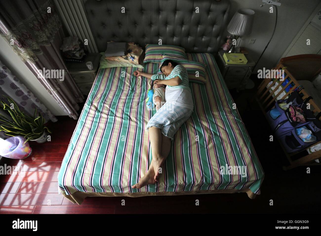 Beijing, China. 31st July, 2016. A mother breastfeeds her baby in bed