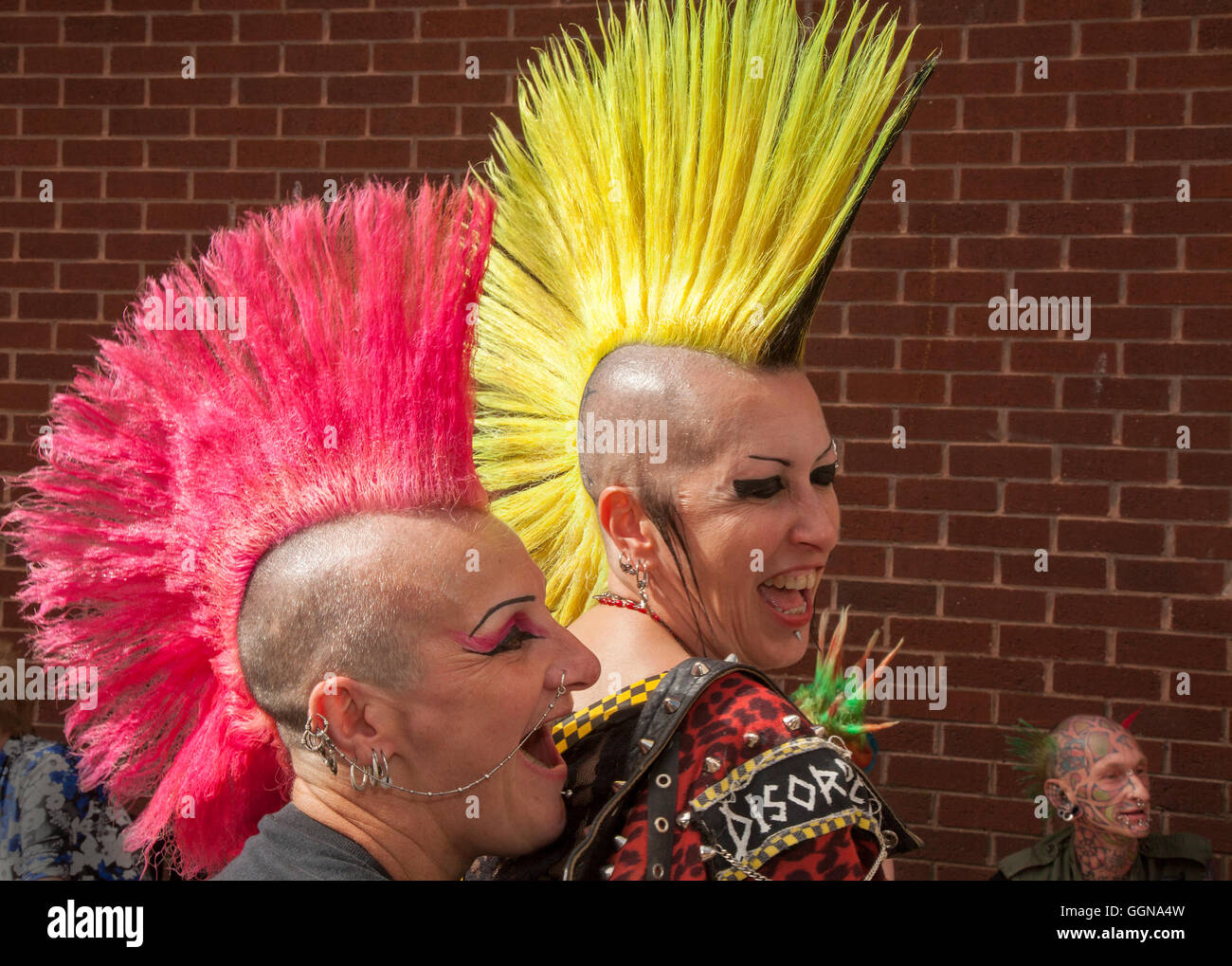A couple with mohawk or Mohican hairstyle with head shaven.  20th anniversary Rebellion fest returned to Blackpool Winter Gardens as one of the world’s biggest punk festivals.  Spiky-haired punks with Mohican hair gathered at the UK’s biggest alternative music festival. The Rebellion Festival sees hard rocking punk bands take to the stage at Blackpool’s Winter Gardens every year to the delight of cheering crowds. The resort’s streets are painted every colour of the rainbow as lifelong punk fans with vividly dyed Mohawks, red yellow spiky mohican leather jackets flock to the Festival Stock Photo