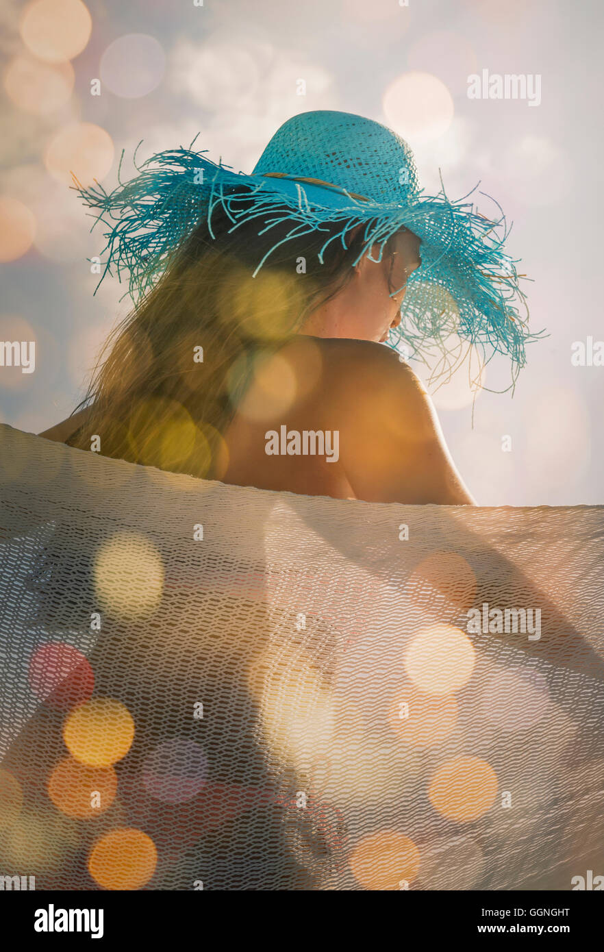 Caucasian woman wearing sun hat in hammock Stock Photo