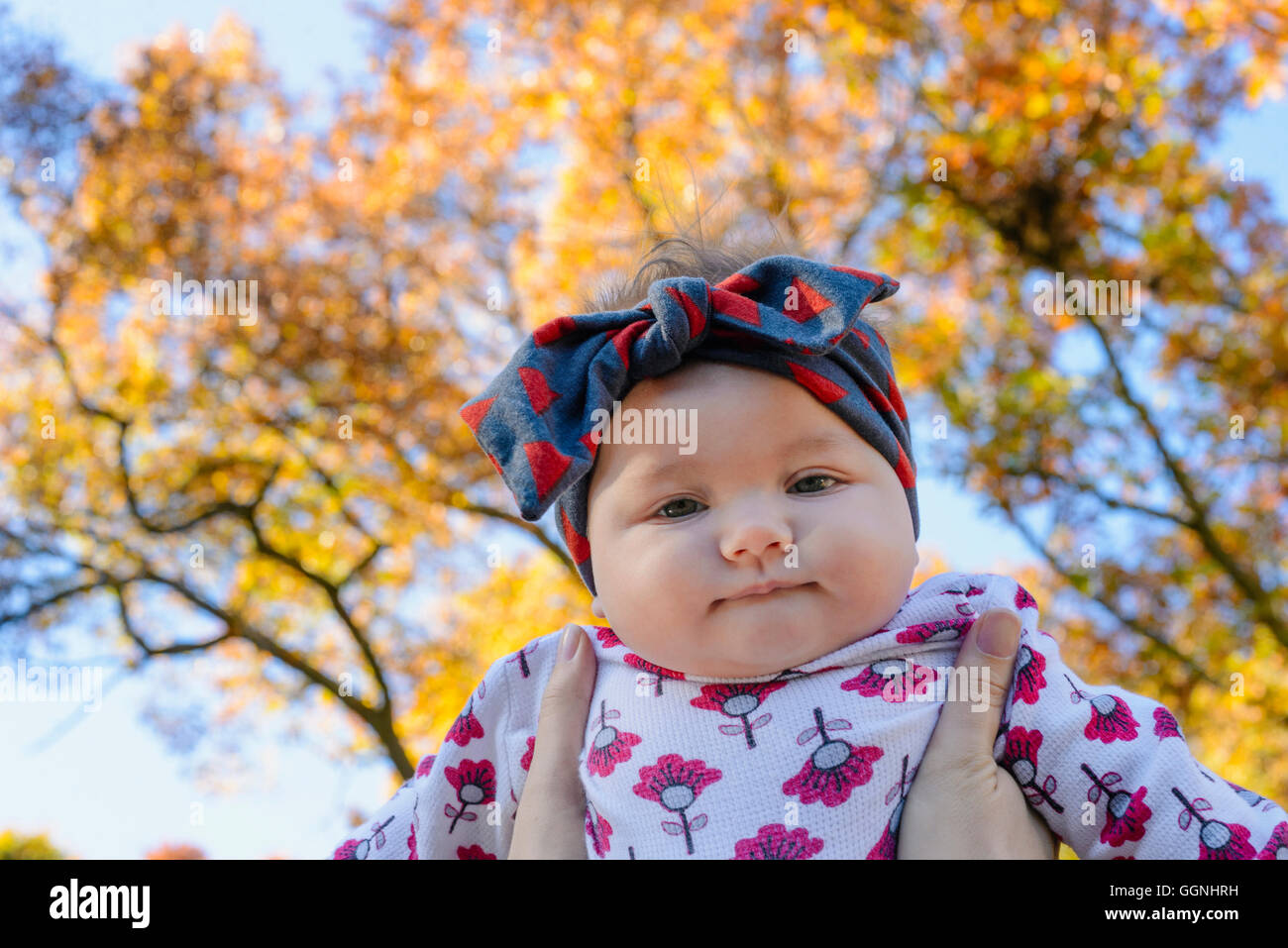 Woman holding baby girl against autumn tree Stock Photo