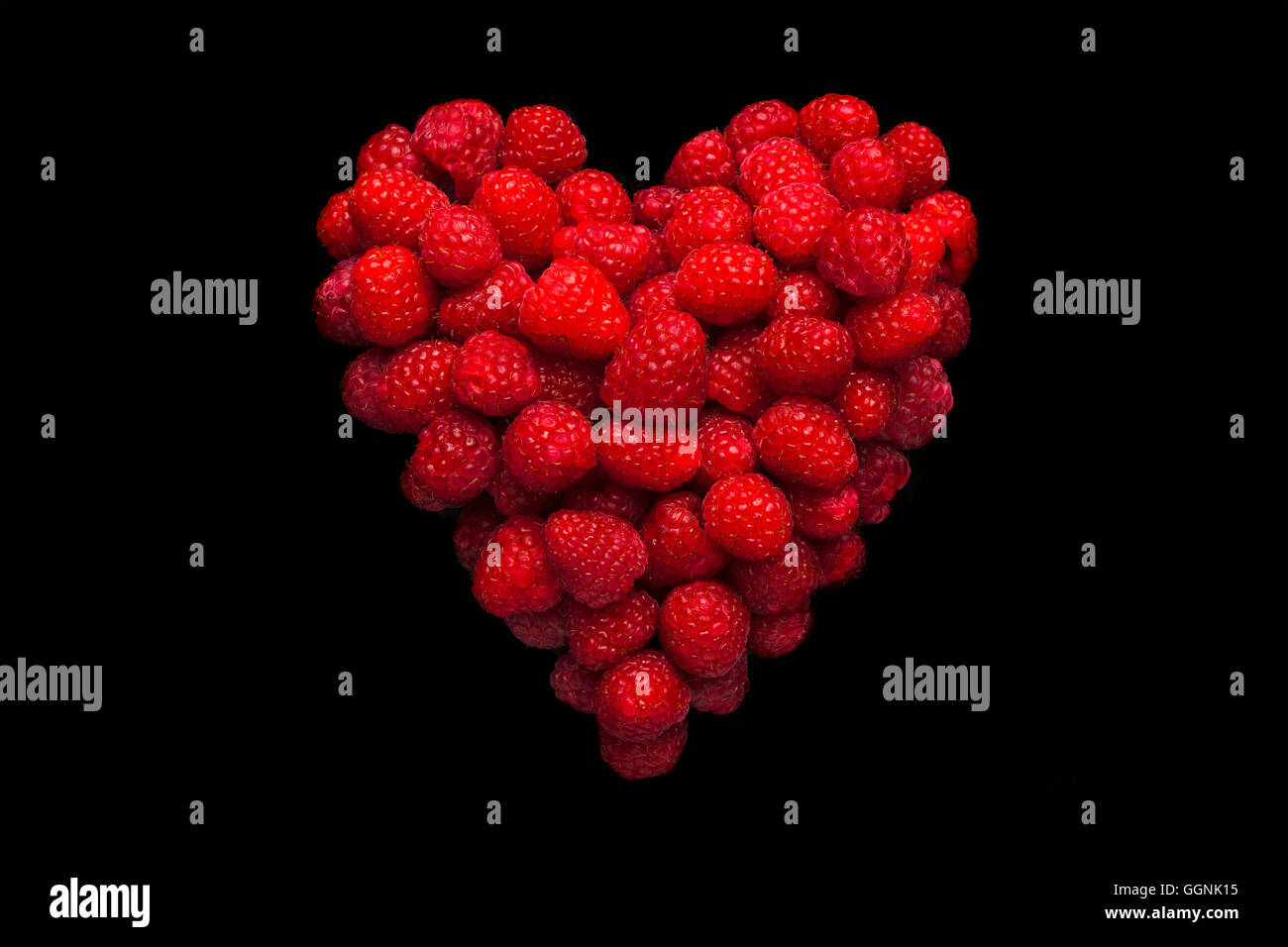 Raspberries in shape of heart on black background Stock Photo