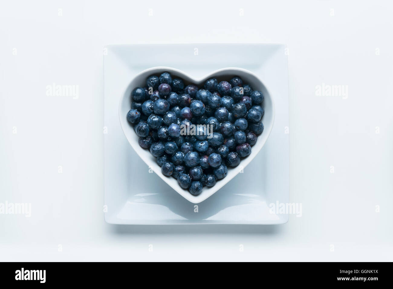 Blueberries in heart-shape bowl on white background Stock Photo