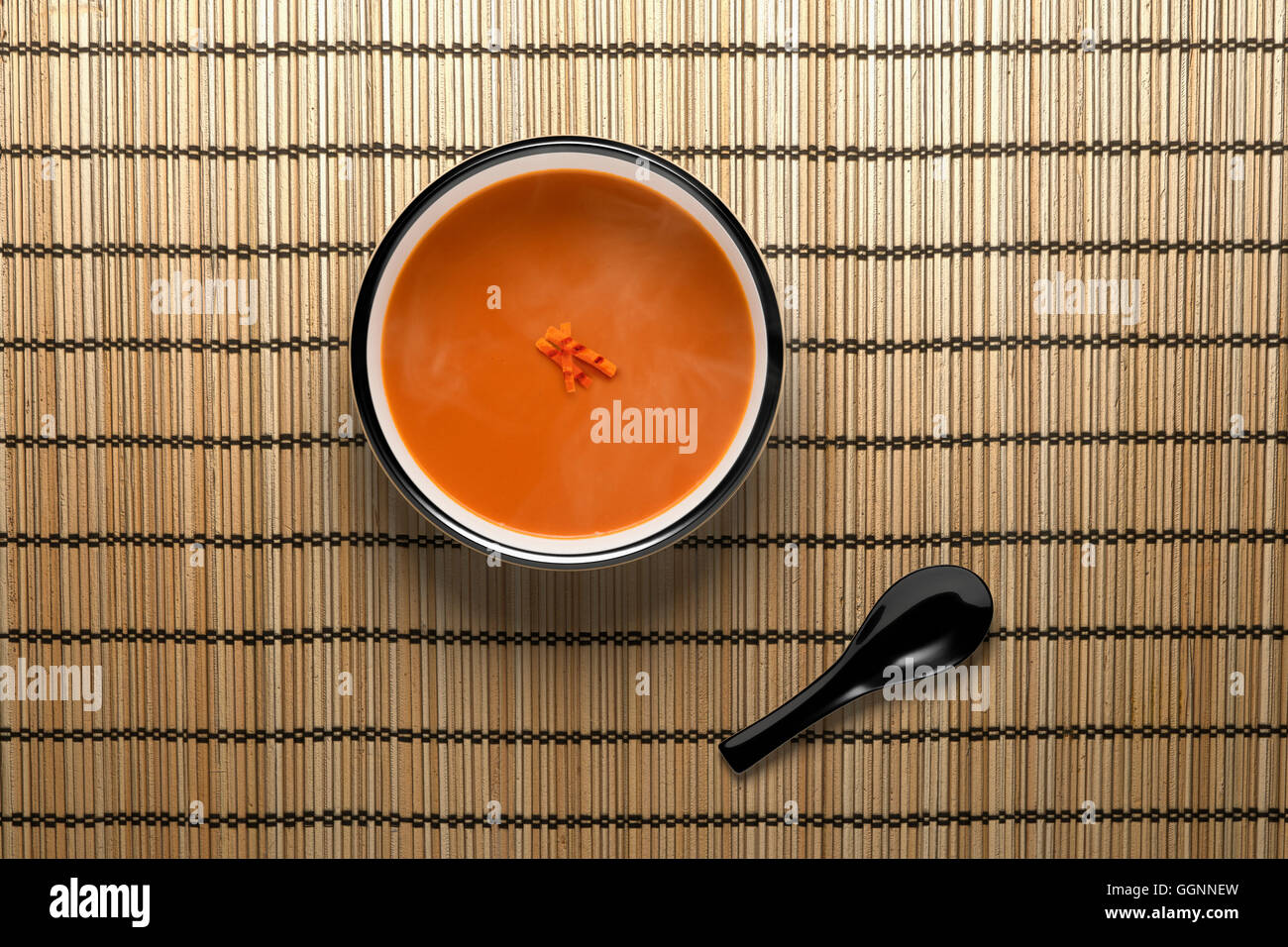 Orange soup in bowl with black spoon Stock Photo