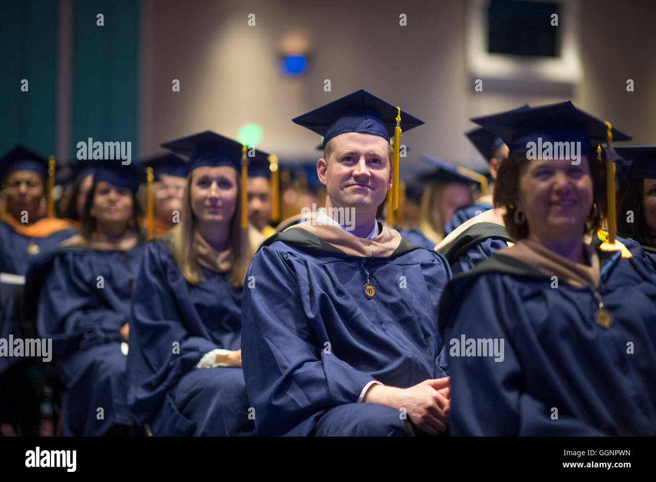 Graduation candidates in caps and gowns wait to receive diplomas at