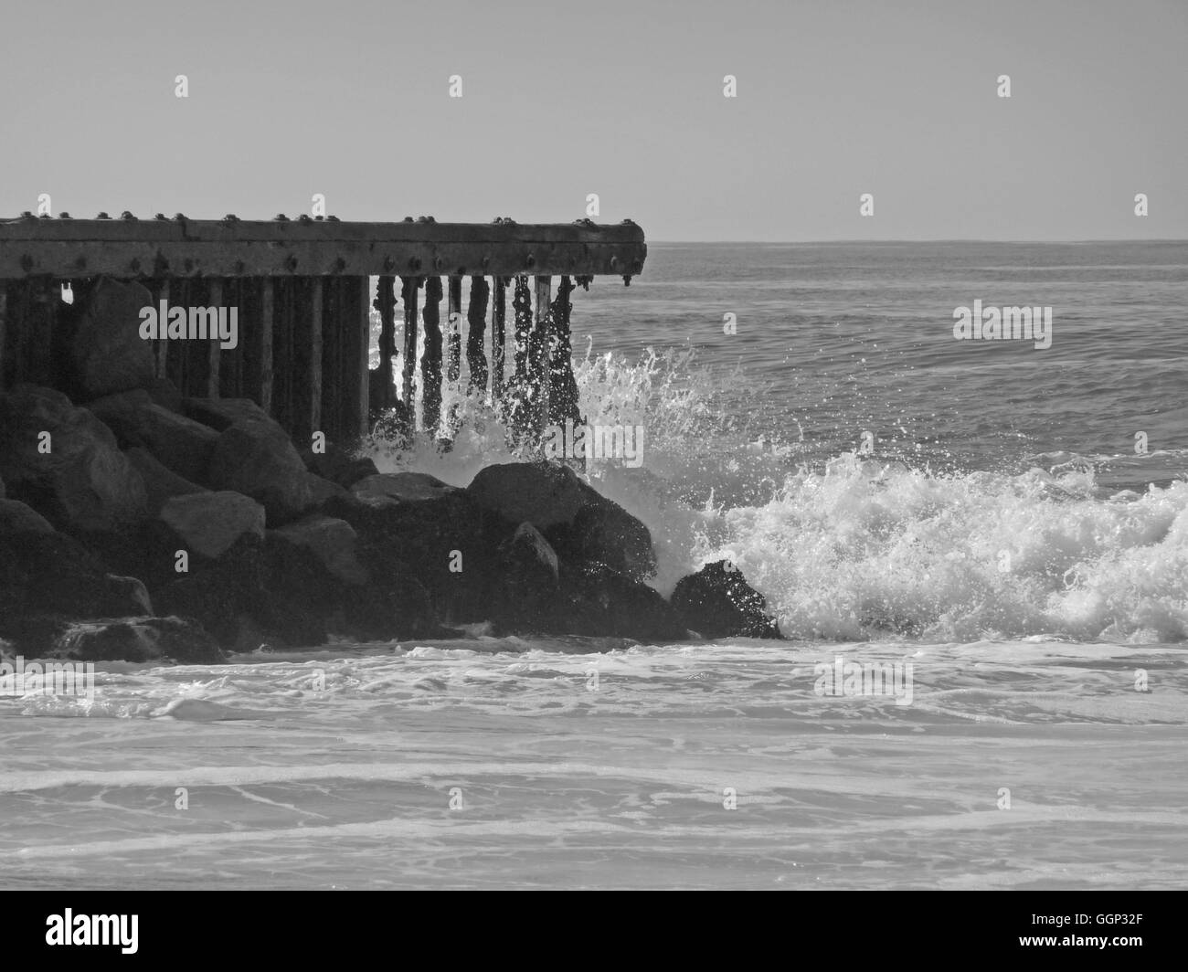 Black and white image of wave crashing on ocean pier Stock Photo - Alamy