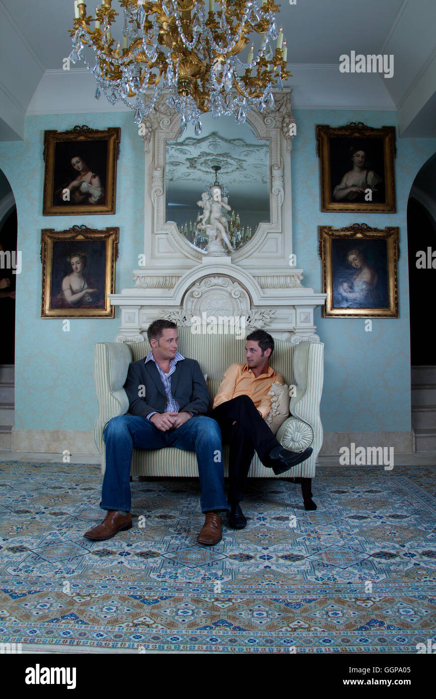 Men staring face to face in loveseat Stock Photo Alamy