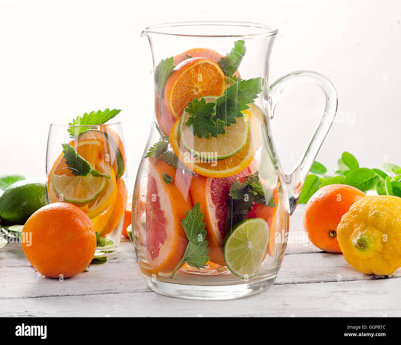 Pitcher and glass with fresh citrus fruits and mint leaves. Stock Photo